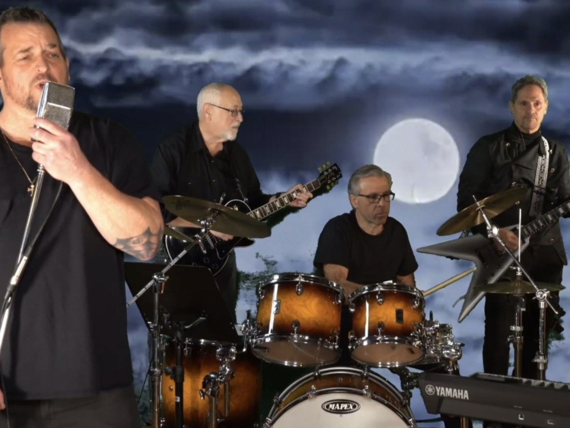 A band performing with five men, one singing into a microphone, the others playing guitars and drums, against a backdrop of a full moon and dark clouds.