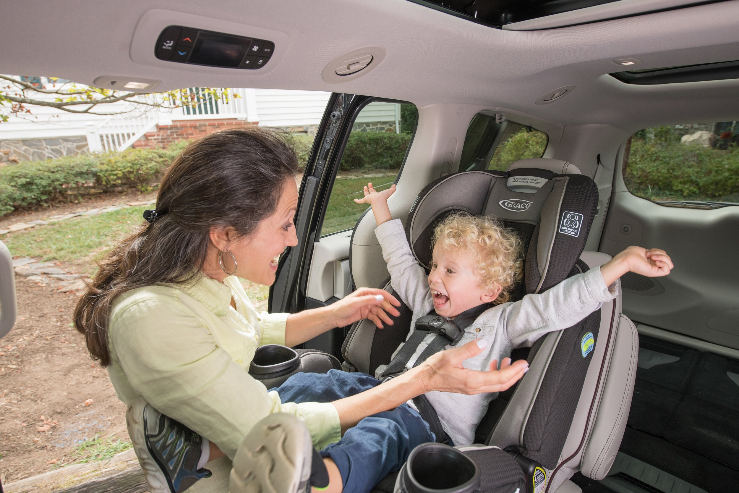 Mother helping excited child get into car seat