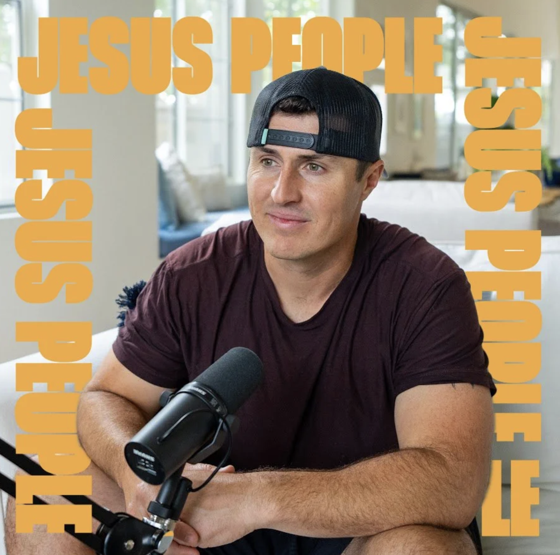 Ryan Miller  wearing a backward black cap and a maroon t-shirt sits at a table with a microphone, smiling slightly. The background shows a bright room with large windows, and the image has bold yellow text overlay that reads "Jesus People" repeated o