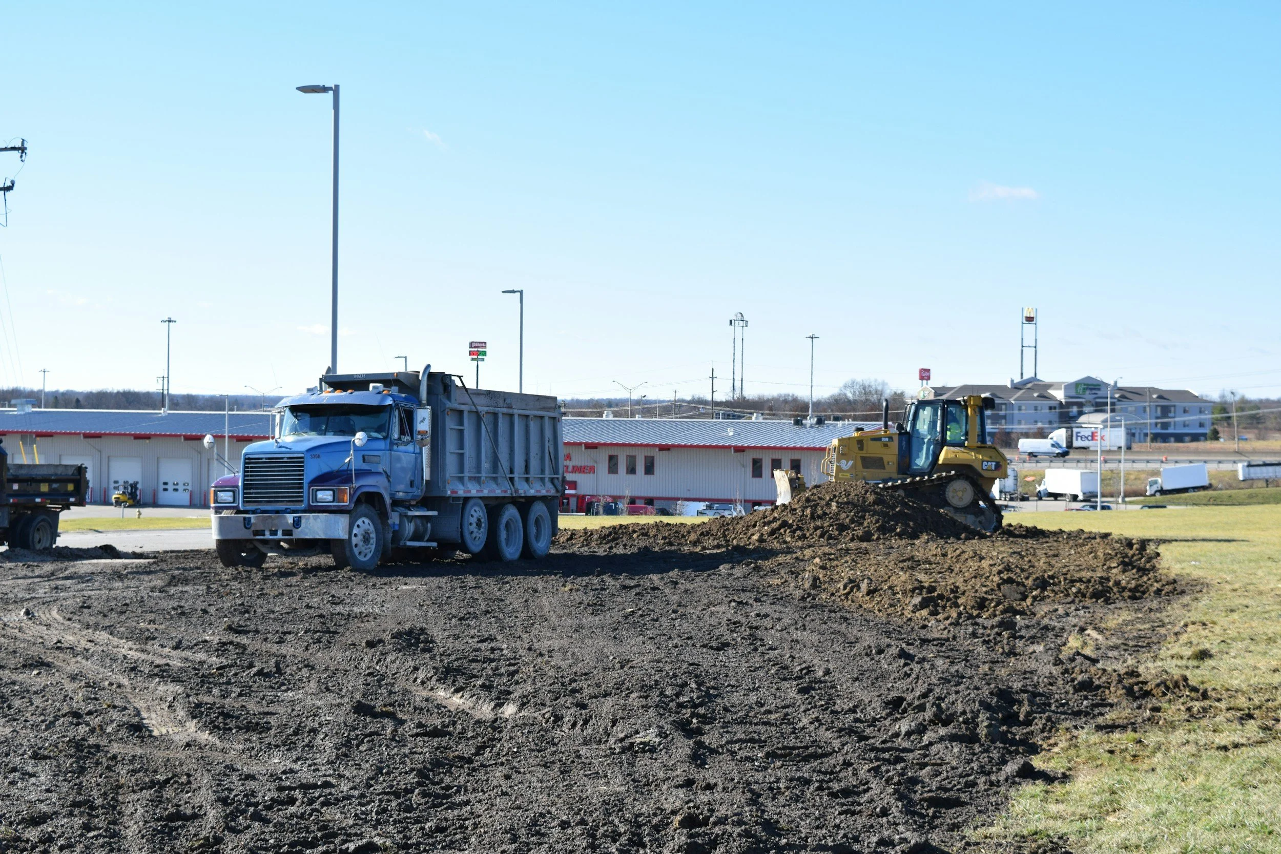Construction site with a blue dump truck and a yellow bulldozer working on leveling dirt