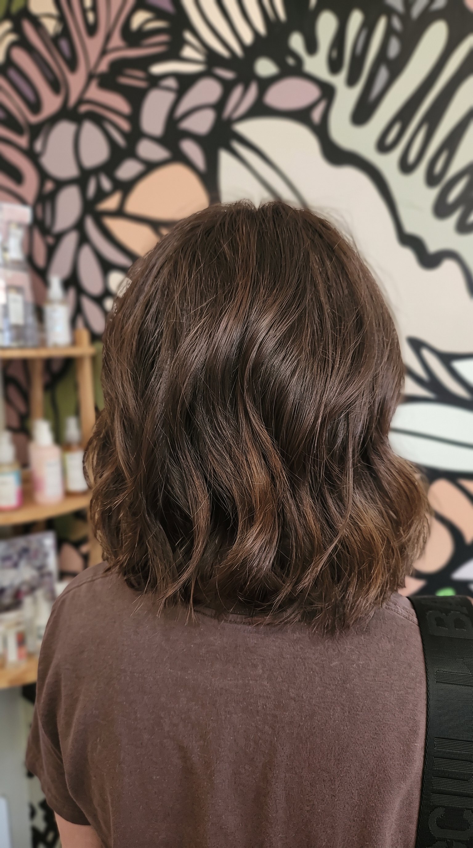 Back view of shoulder-length wavy brown hair in a salon