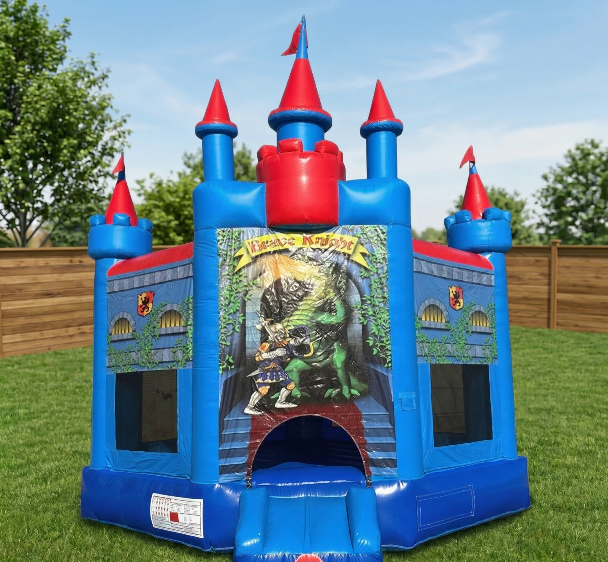 Colorful inflatable castle with a medieval theme, featuring knights fighting a dragon, surrounded by a wooden fence and green grass.