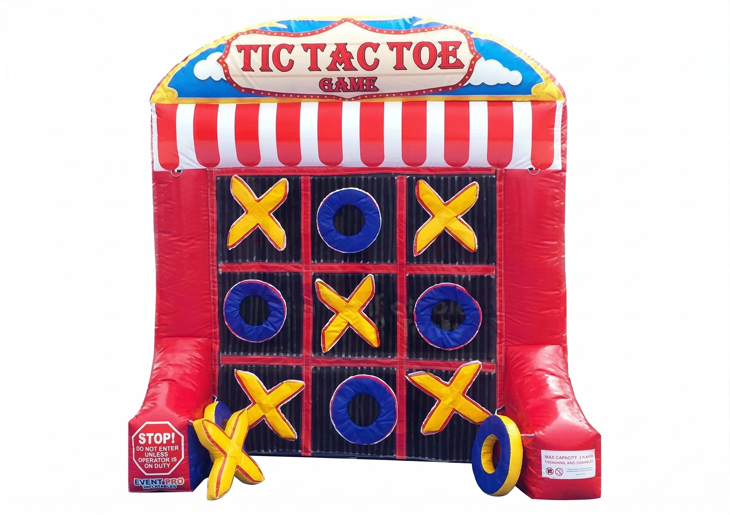 An inflatable giant tic-tac-toe game with a red and white striped awning. Four yellow X's and four blue O's are visible on the game grid. There are additional inflatable X and O pieces at the base of the game.