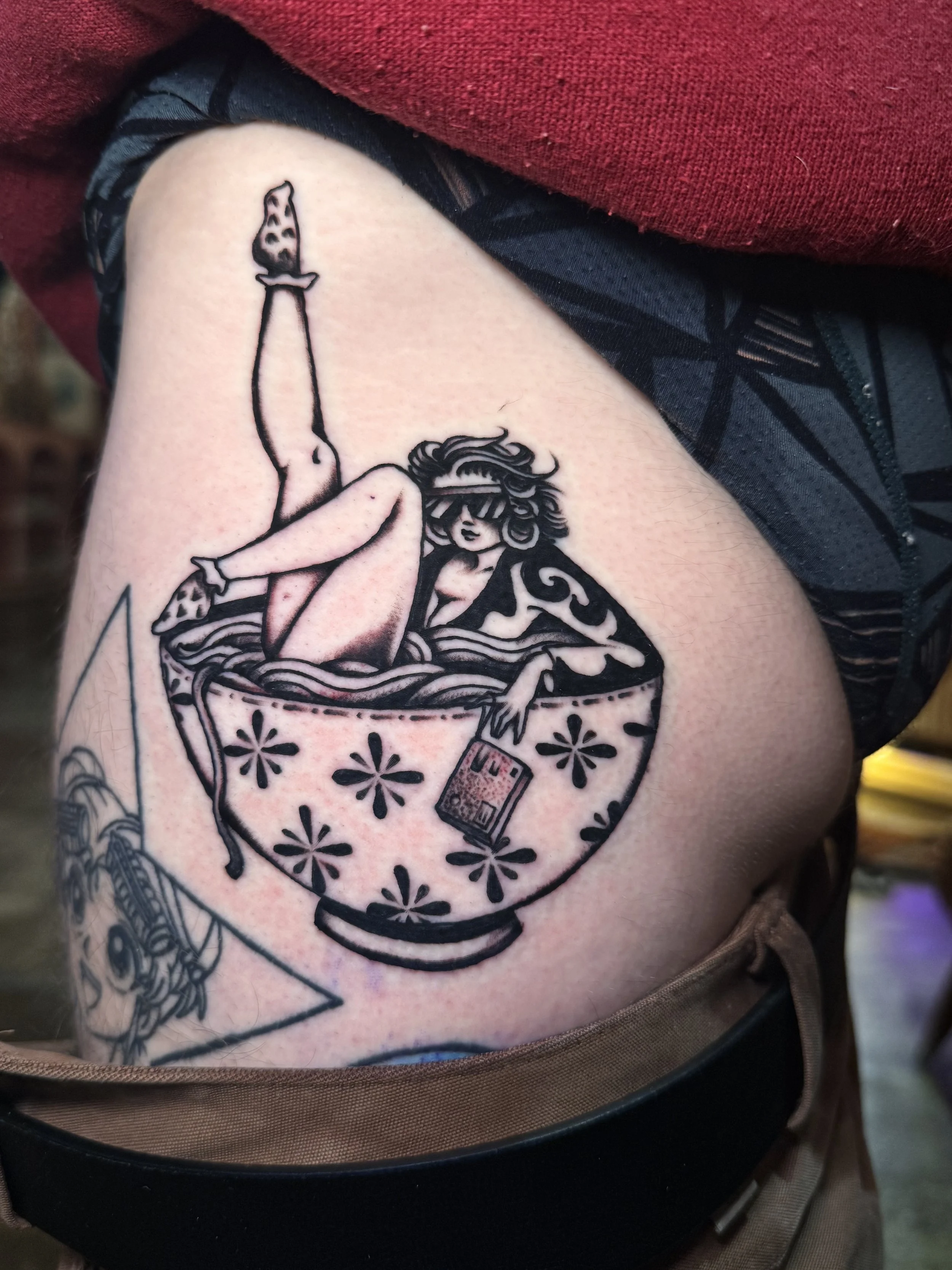 my cousin vinny inspired tattoo picturing a woman holding a camera posing inside of a ramen bowl