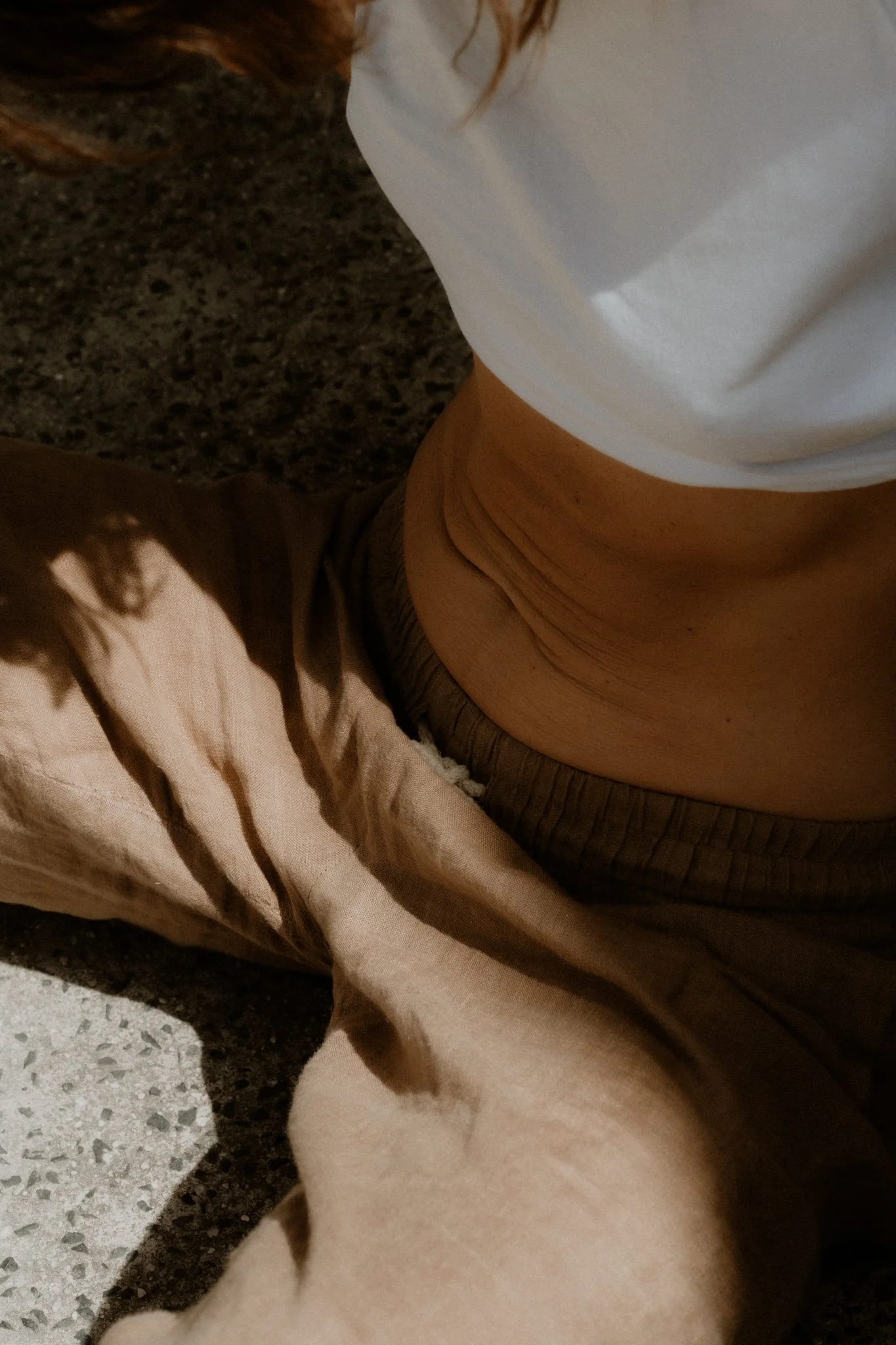 Natural light on the abdomen of a relaxed client at Flow Therapy Byron Bay, representing gut‑body connection and inner calm.