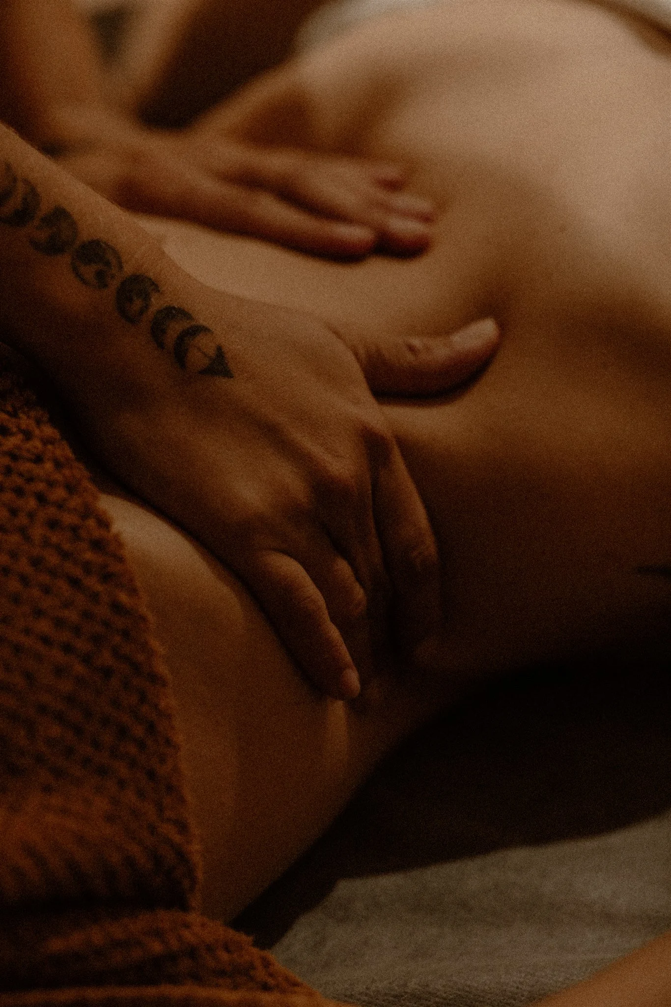 close up of a deep therapeutic abdomal massage, tattoos visible on the masseuses hand.