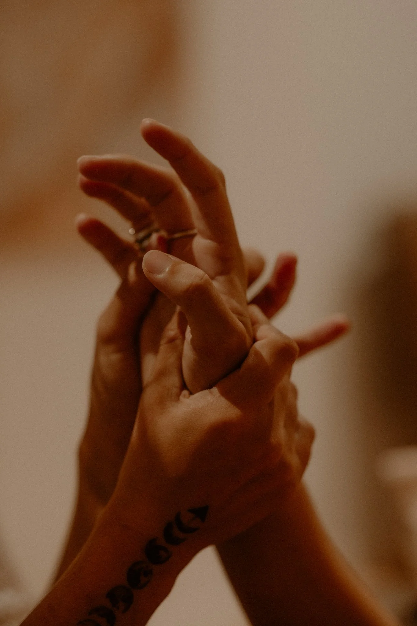 Two people clasping hands in a dance or theatrical performance, with one person's hand wearing rings and a tattoo visible on the wrist.