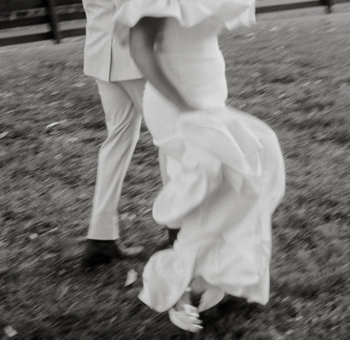 A person in a hat and light-colored clothing crouching in the grass
