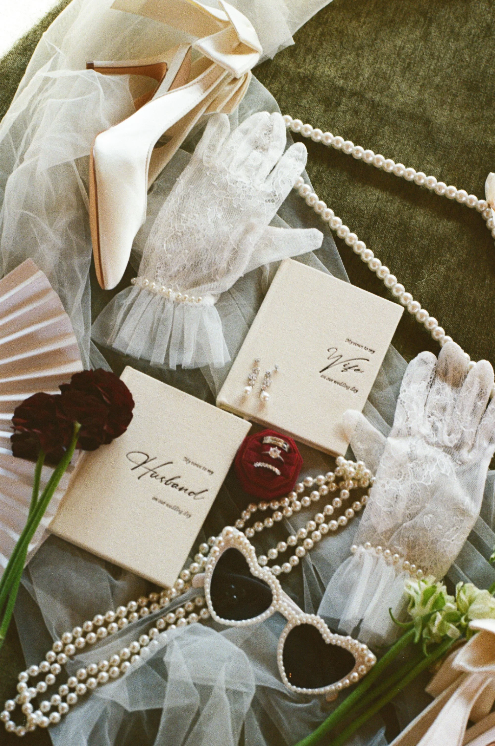 Wedding accessories including white high heels, lace gloves, pearl necklaces, wedding rings, wedding vow books, sunglasses, flowers, and decorative paper fans.