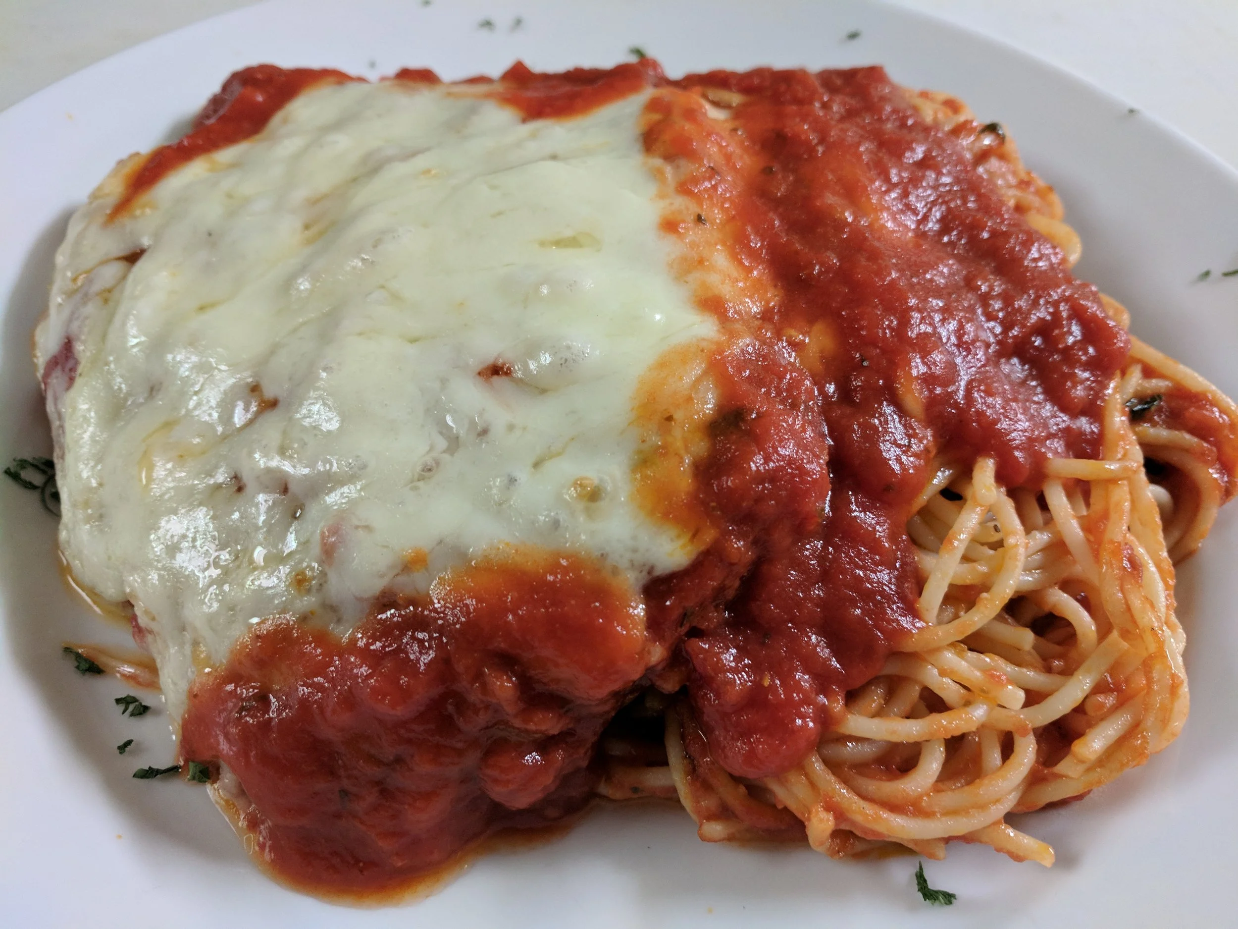 Plate of spaghetti with marinara sauce topped with melted cheese