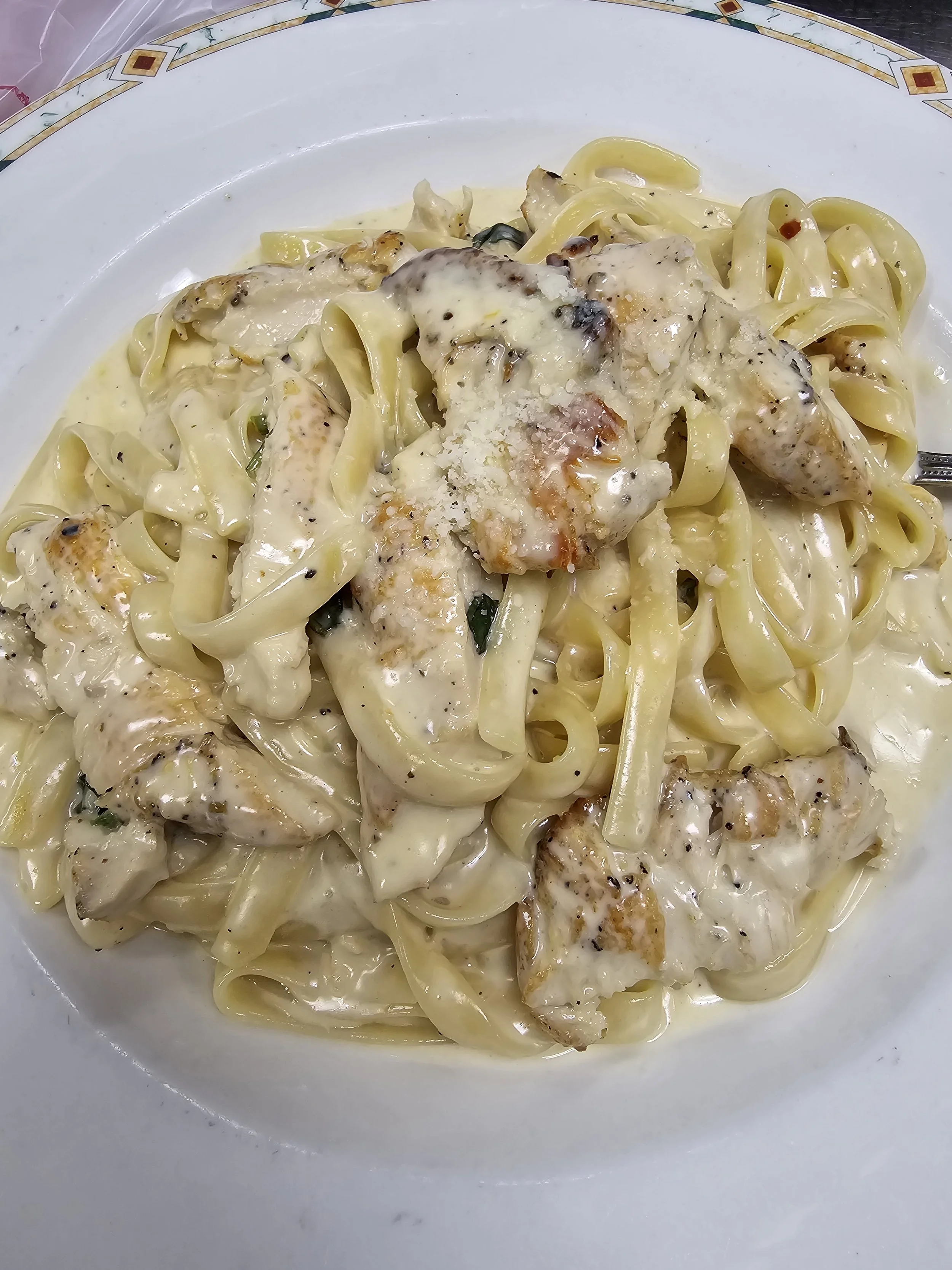 Plate of fettuccine pasta with grilled chicken and creamy Alfredo sauce.