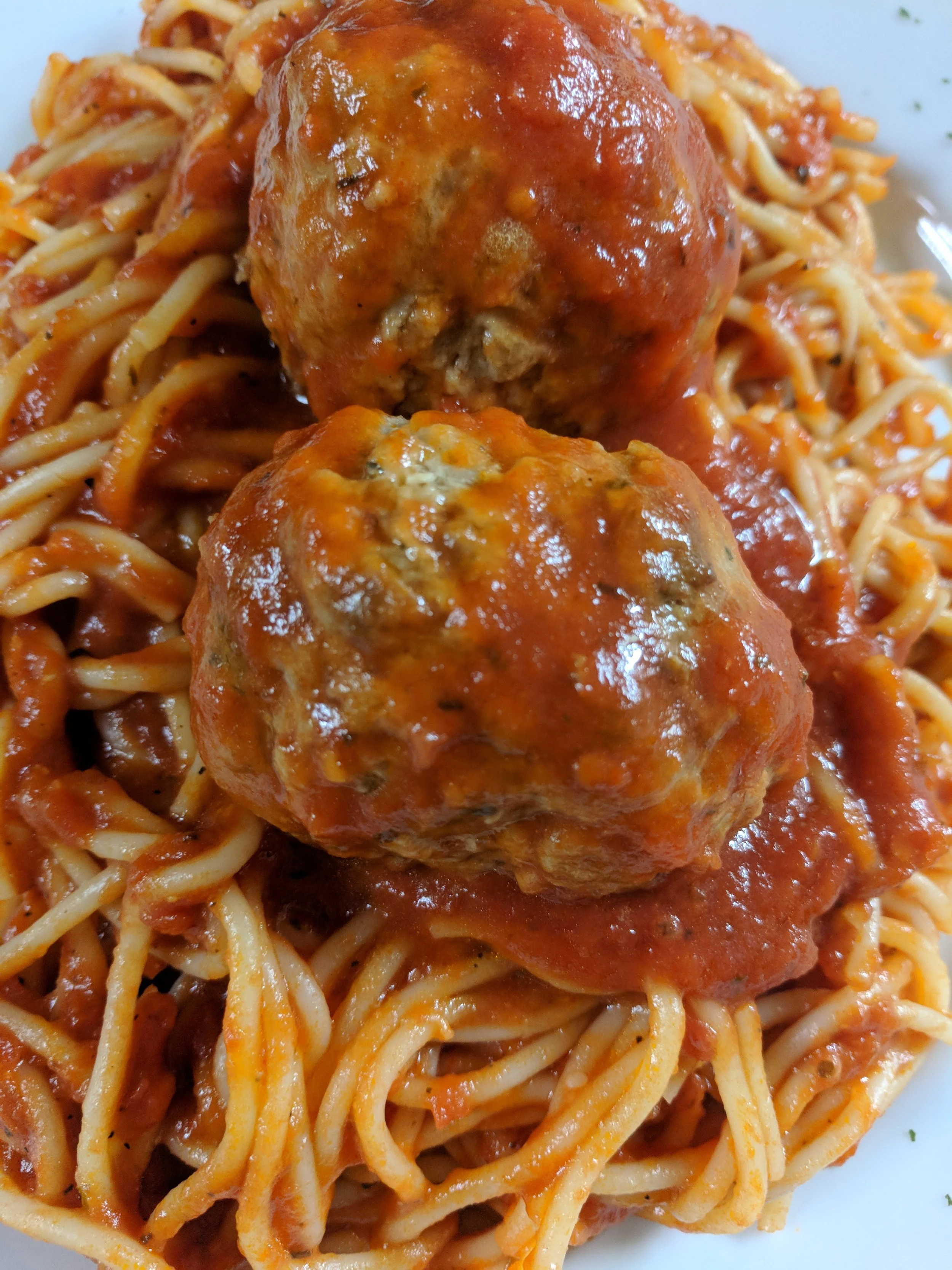 Spaghetti with marinara sauce topped with two meatballs.