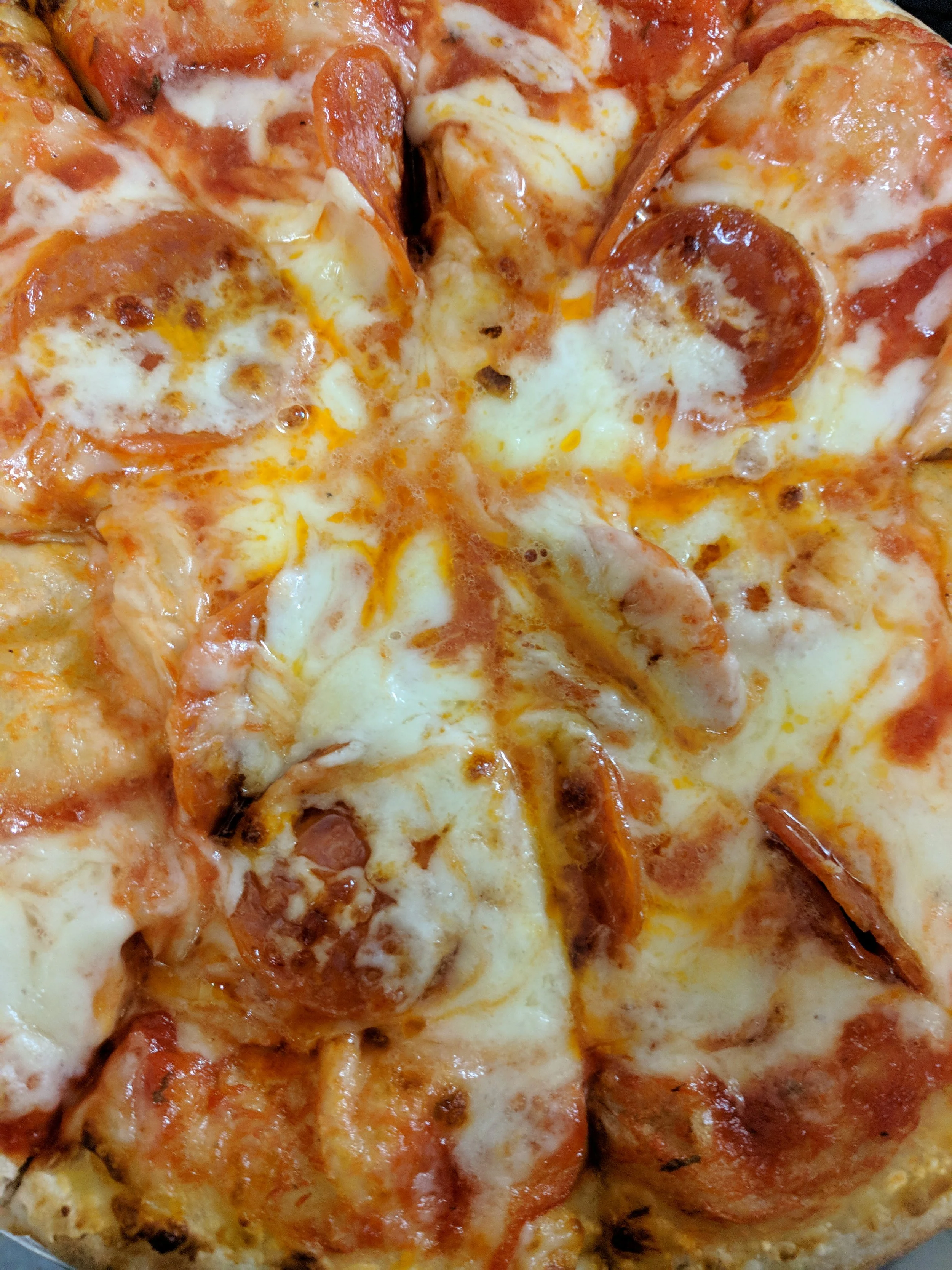 Close-up of a cooked pizza topped with cheese and pepperoni slices.