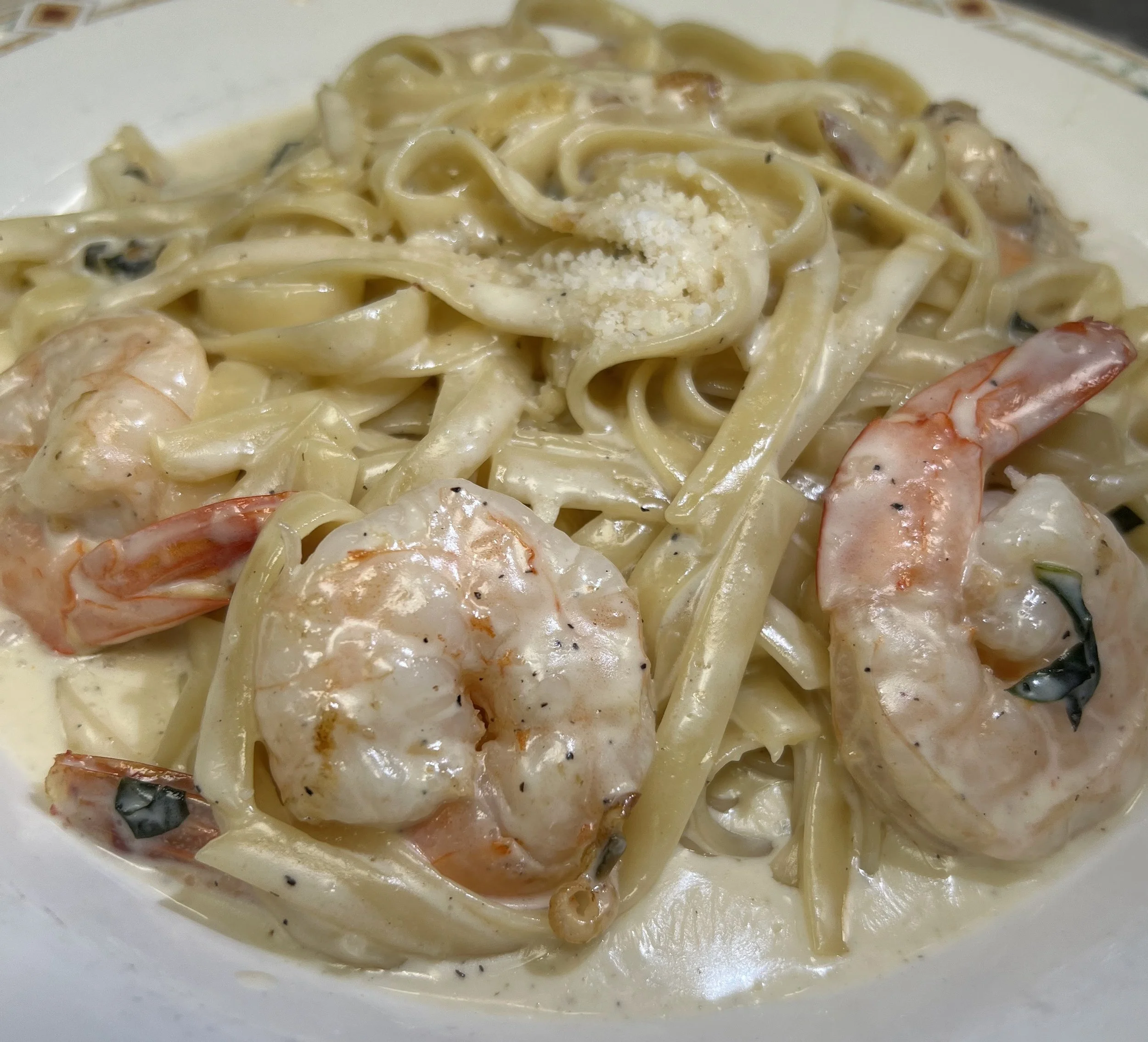 Shrimp and fettuccine pasta in creamy Alfredo sauce with grated cheese topping.
