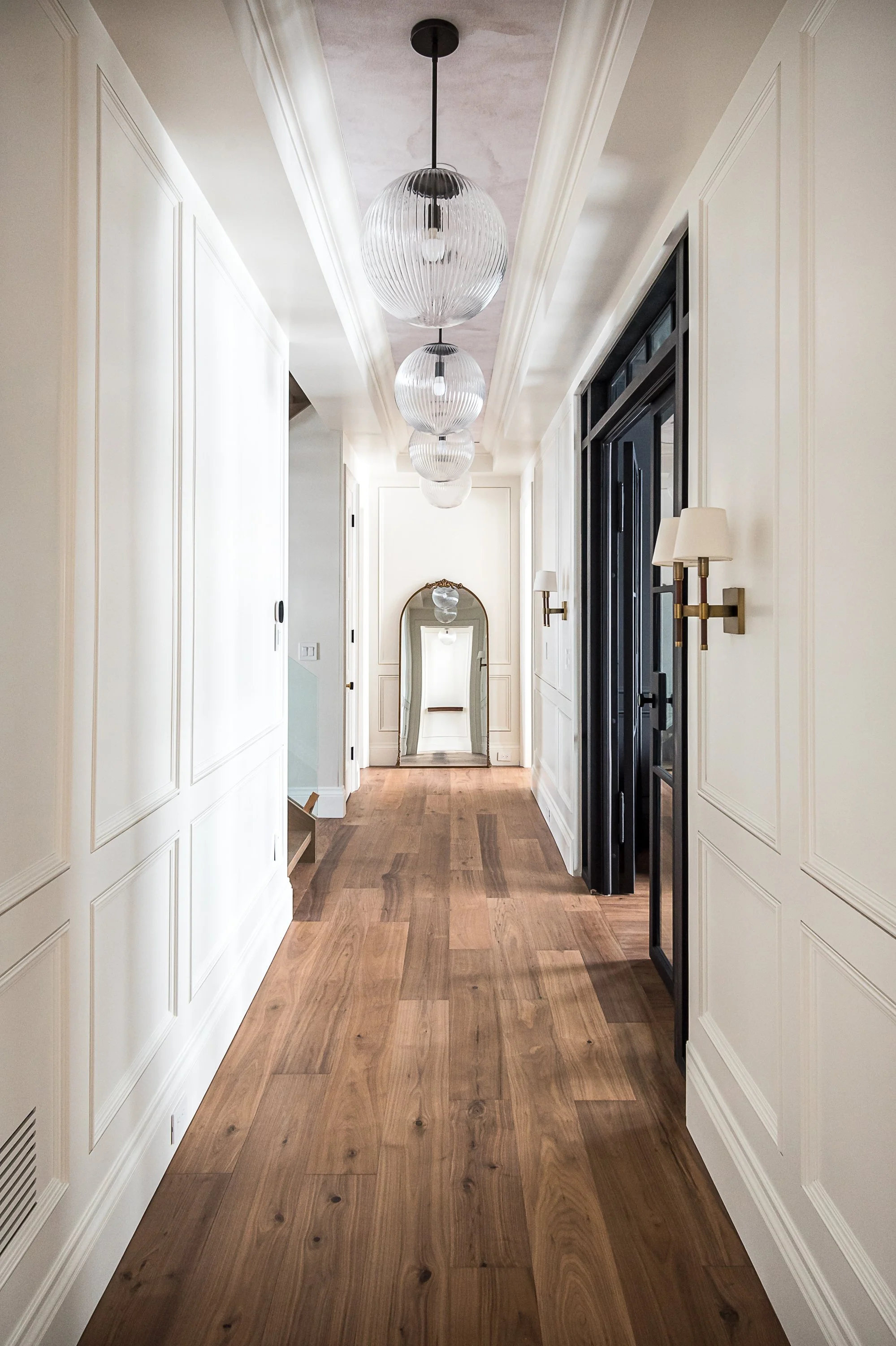 Hallway with panel moulding and statement lighting with wallpapered ceiling interior design in Toronto Ontario by JT & Co Interiors