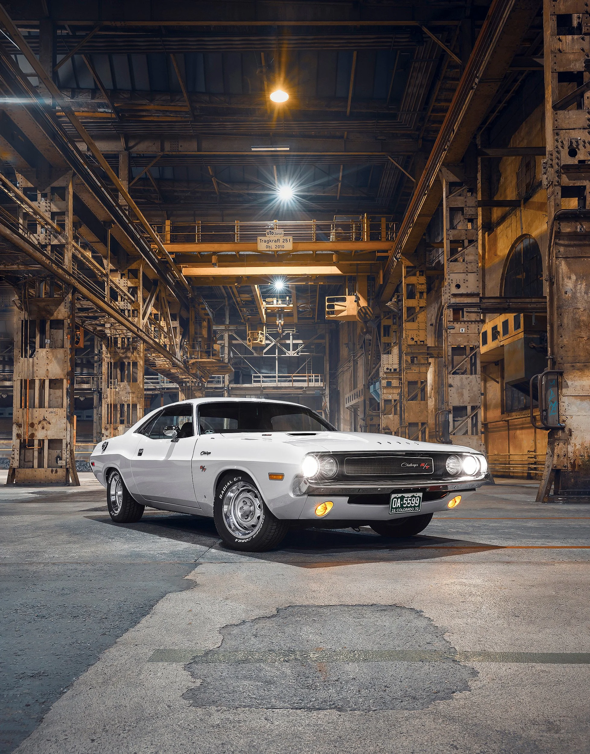 Ein weißer Oldtimer-Auto in einer Lagerhalle mit industriellem Metallgerüst und Beleuchtung