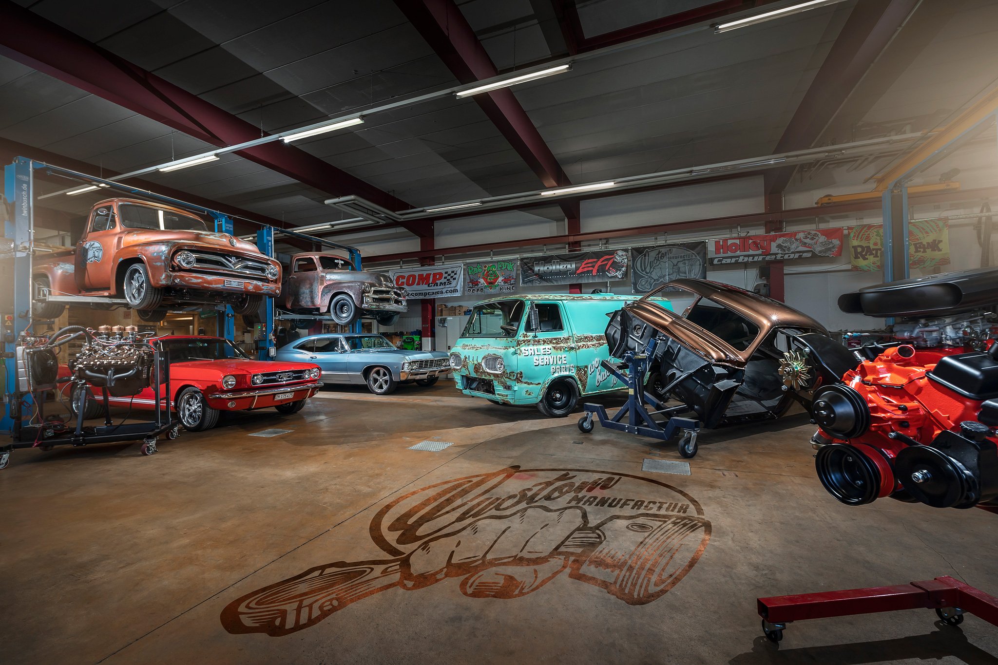 Ein Auto-Werkstatt mit verschiedenen Oldtimern und Autoteilen, darunter ein autobetonter Ford, Fahrzeuge auf Hebebühnen, Werkzeuge und Werbebanner im Hintergrund.