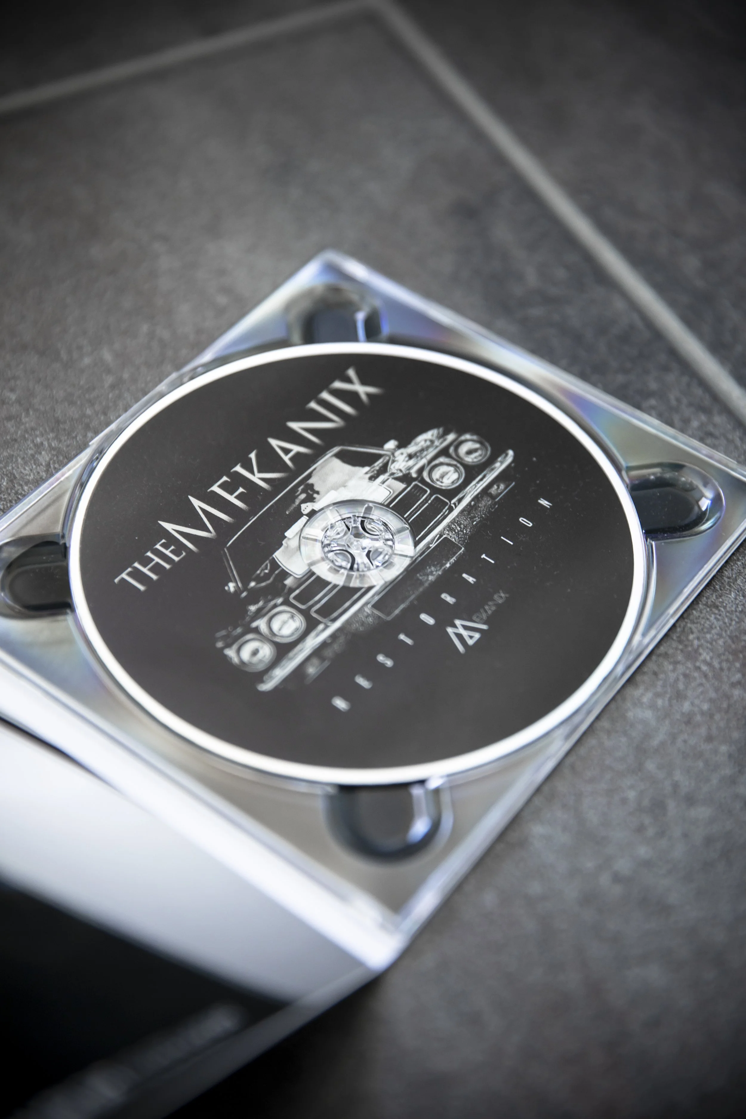 Eine CD in einer transparenten Hülle mit einem schwarzen Cover, das den Titel 'The Mekanix' trägt.