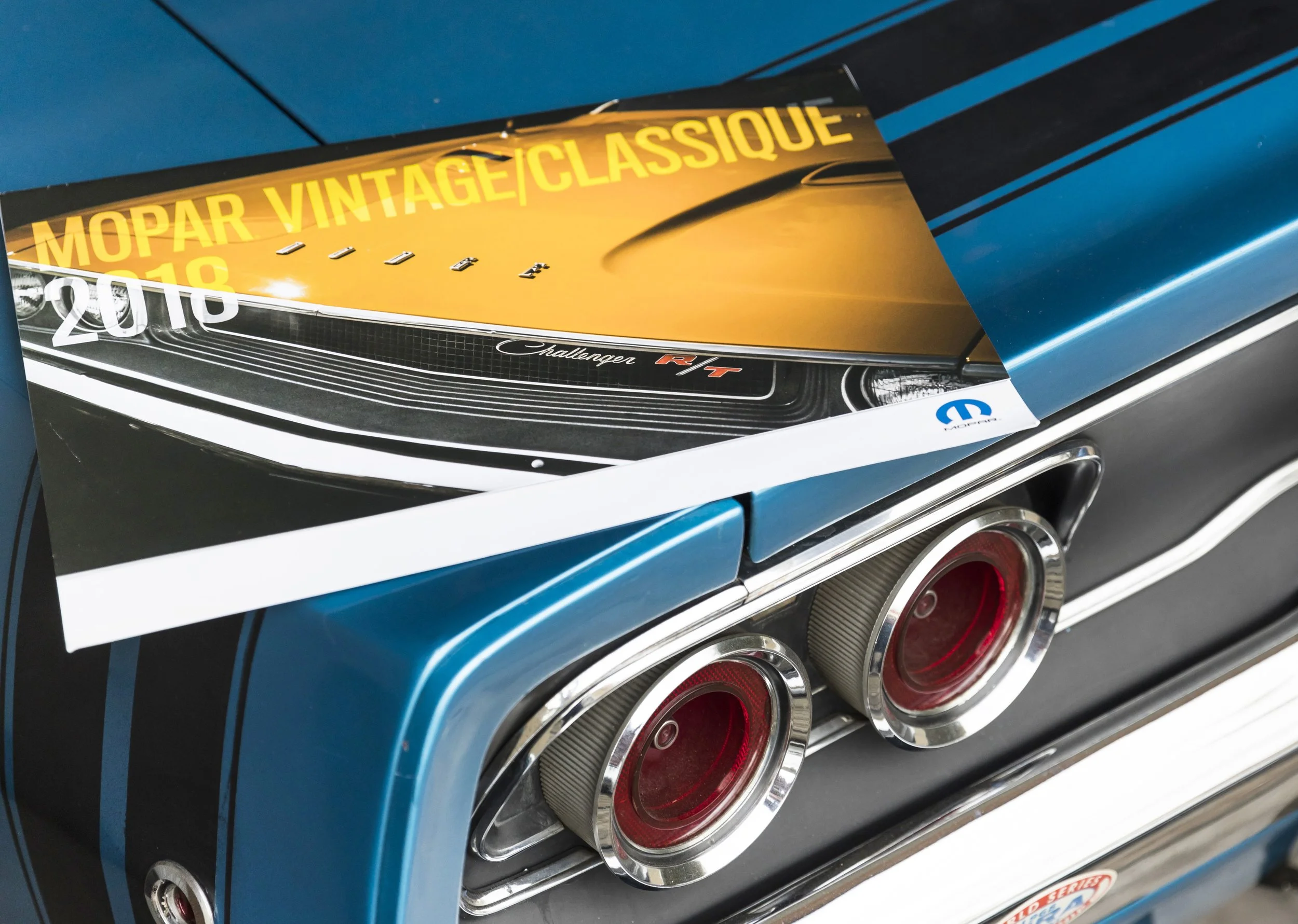 Ein Auto mit den Schriftzügen 'MOPAR VINTAGE | CLASSIQUE' auf der Motorhaube und runden roten Rücklichtern.