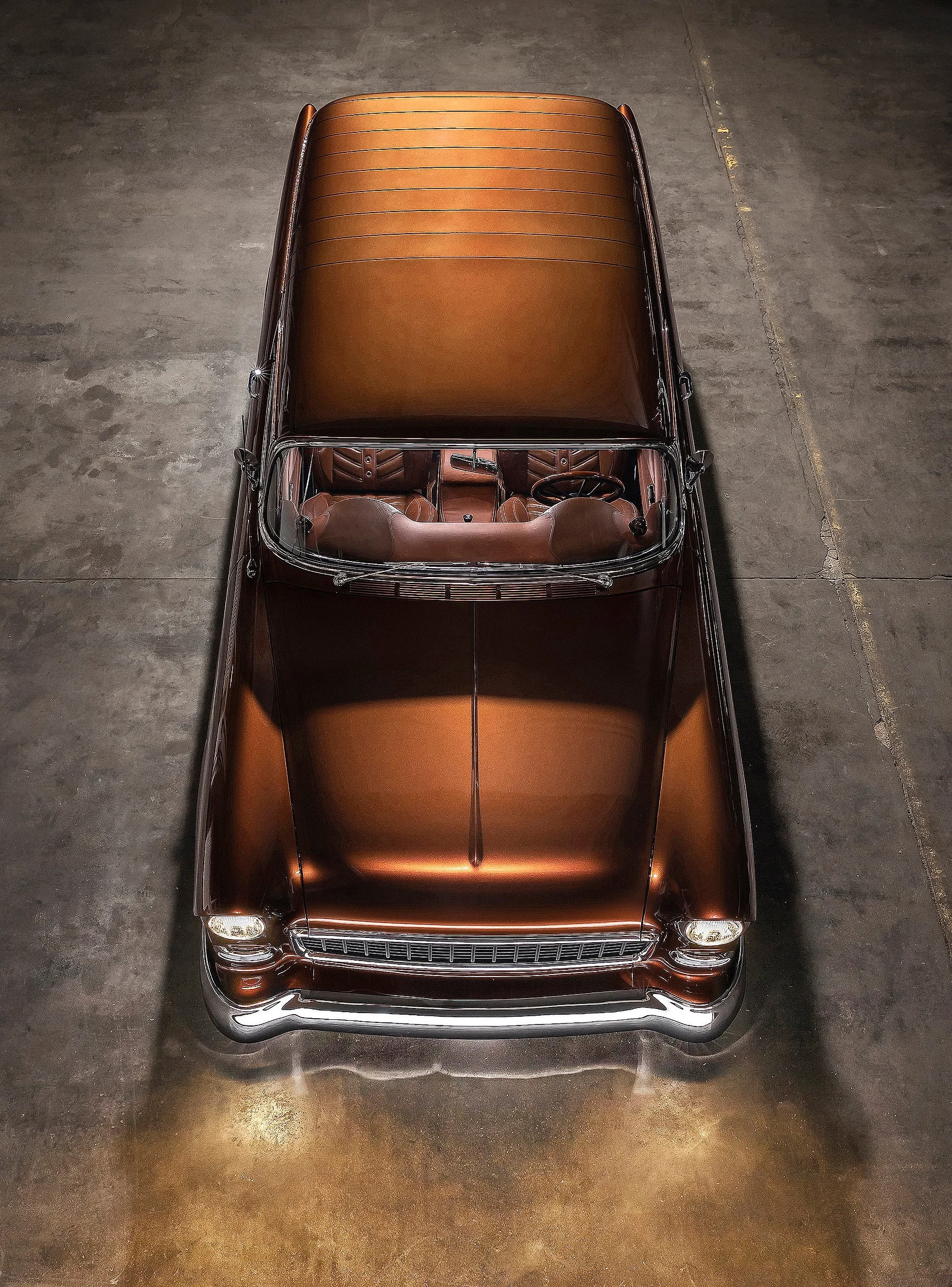 Ein stilvolles klassisches Auto mit braunem Interieur, aufgenommen von oben auf einer dunklen, grauen Bodenfläche.