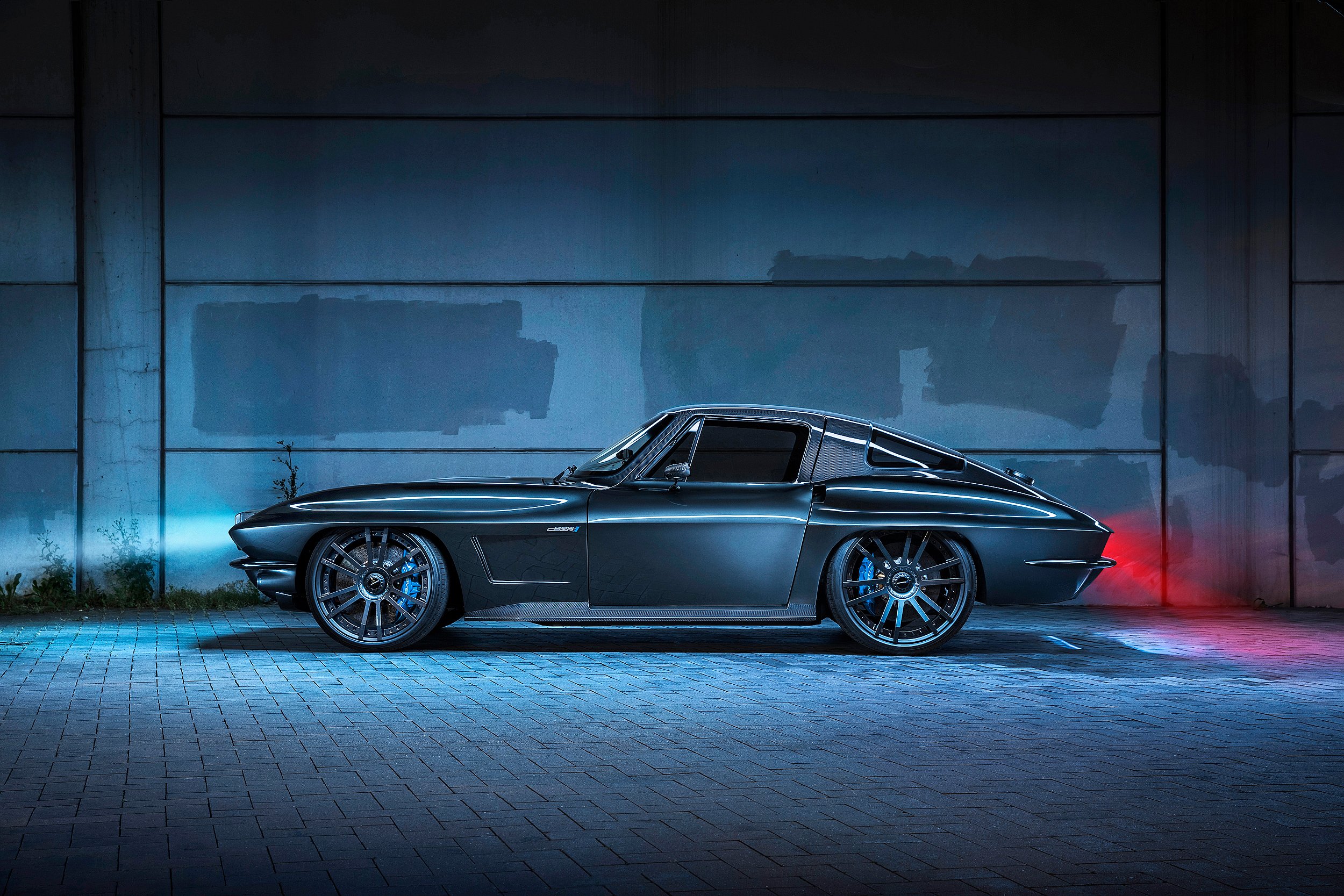 Ein schwarzes Sportauto steht vor einer dunklen Wand, beleuchtet mit blauen und roten Lichtern. Das Fahrzeug ist modern und futuristisch gestaltet.