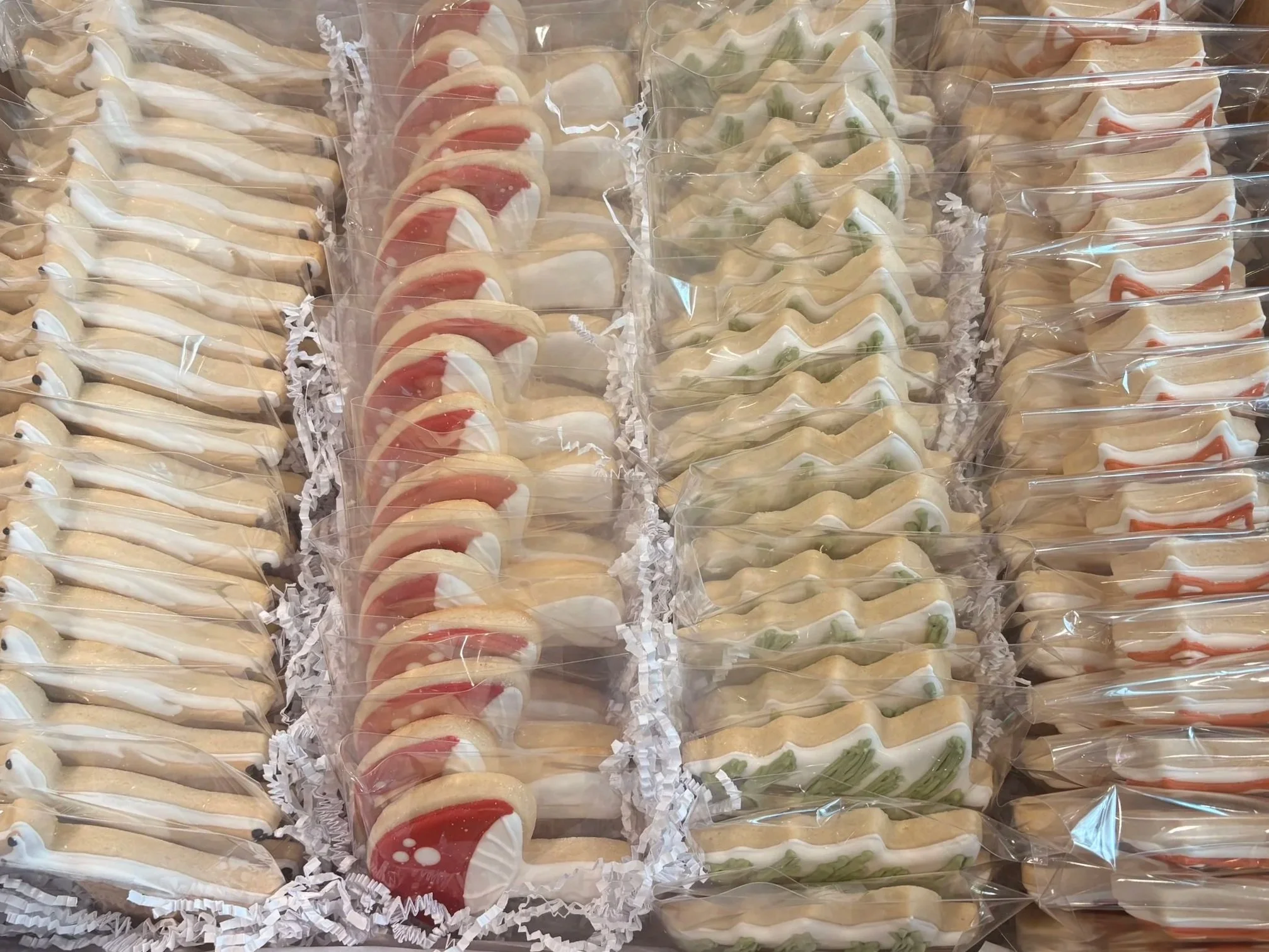 Display of assorted cookies individually wrapped in clear plastic packaging, arranged in rows on a flat surface.