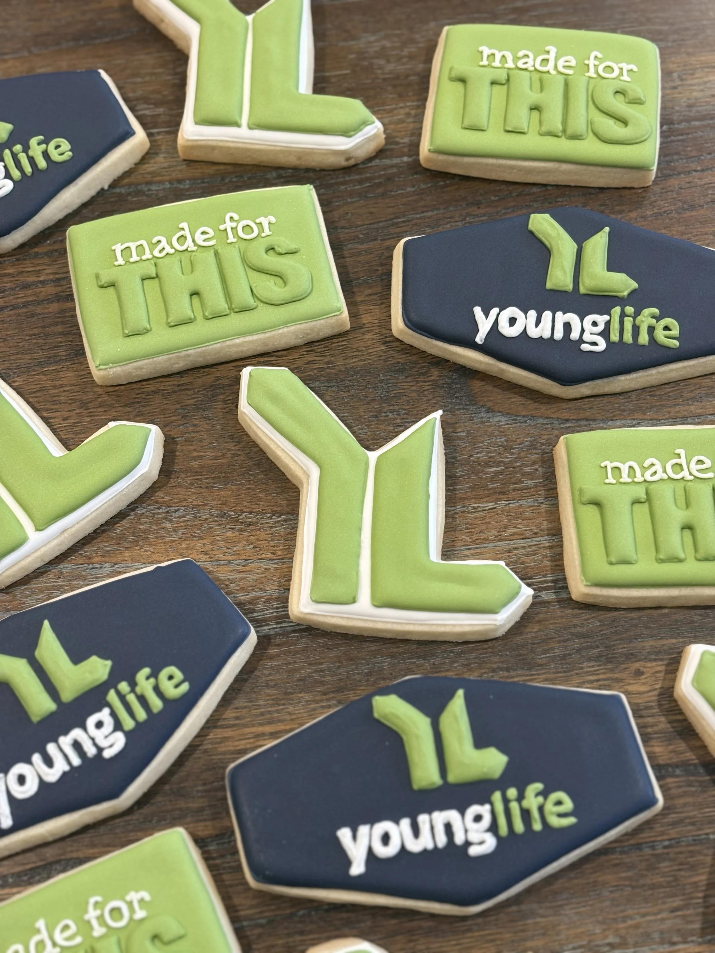Decorative cookies with the phrases 'made for THIS', 'made for THIS', and 'young life' in colored icing, placed on a wooden surface.