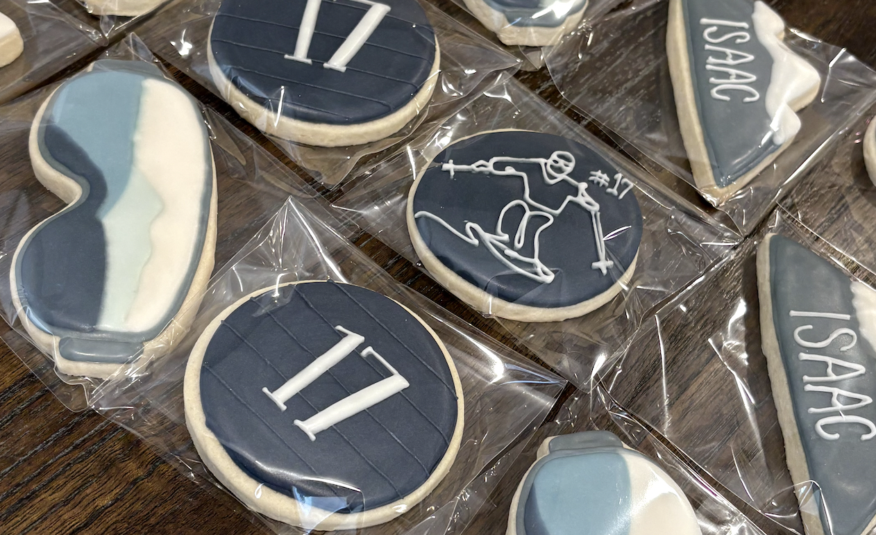 Cookies decorated with sports and team logos, including the St. Louis Blues hockey team, with some cookies featuring the #11 and #17 player numbers and a hockey player silhouette, all wrapped in clear plastic.