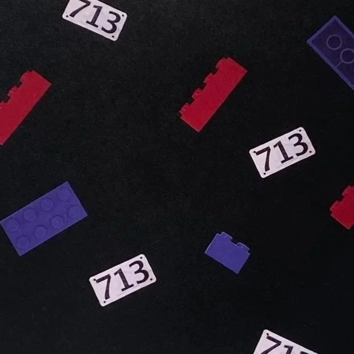Lego bricks and tiles scattered on a black background, including white tiles with the number 713, red bricks, and purple bricks.
