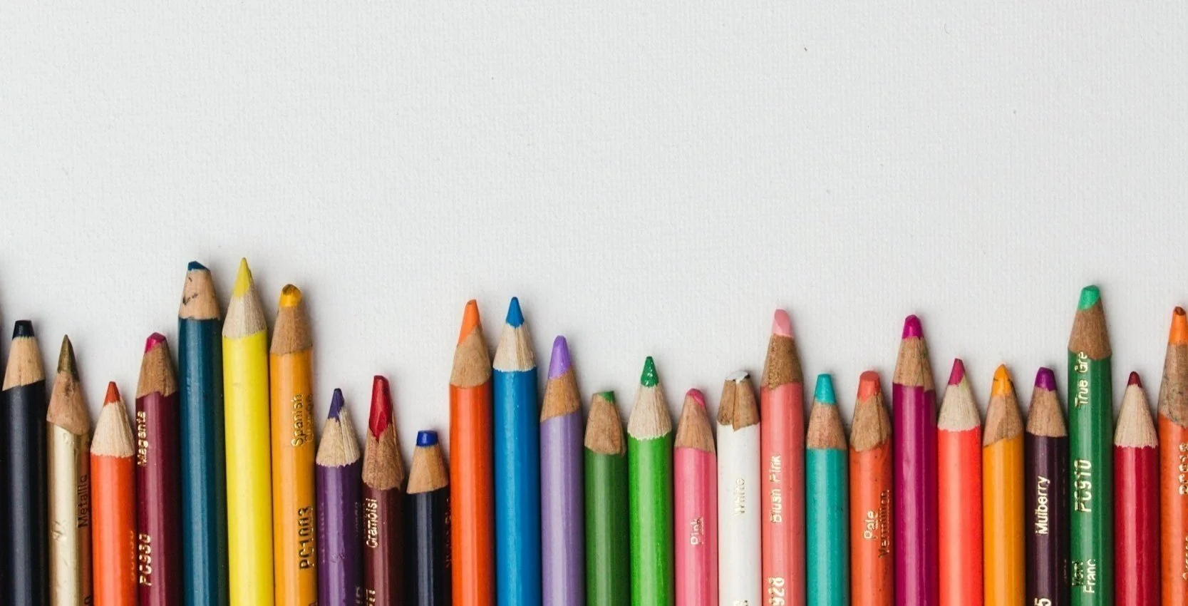 Color pencils lined up with sharpened tips on a white background.