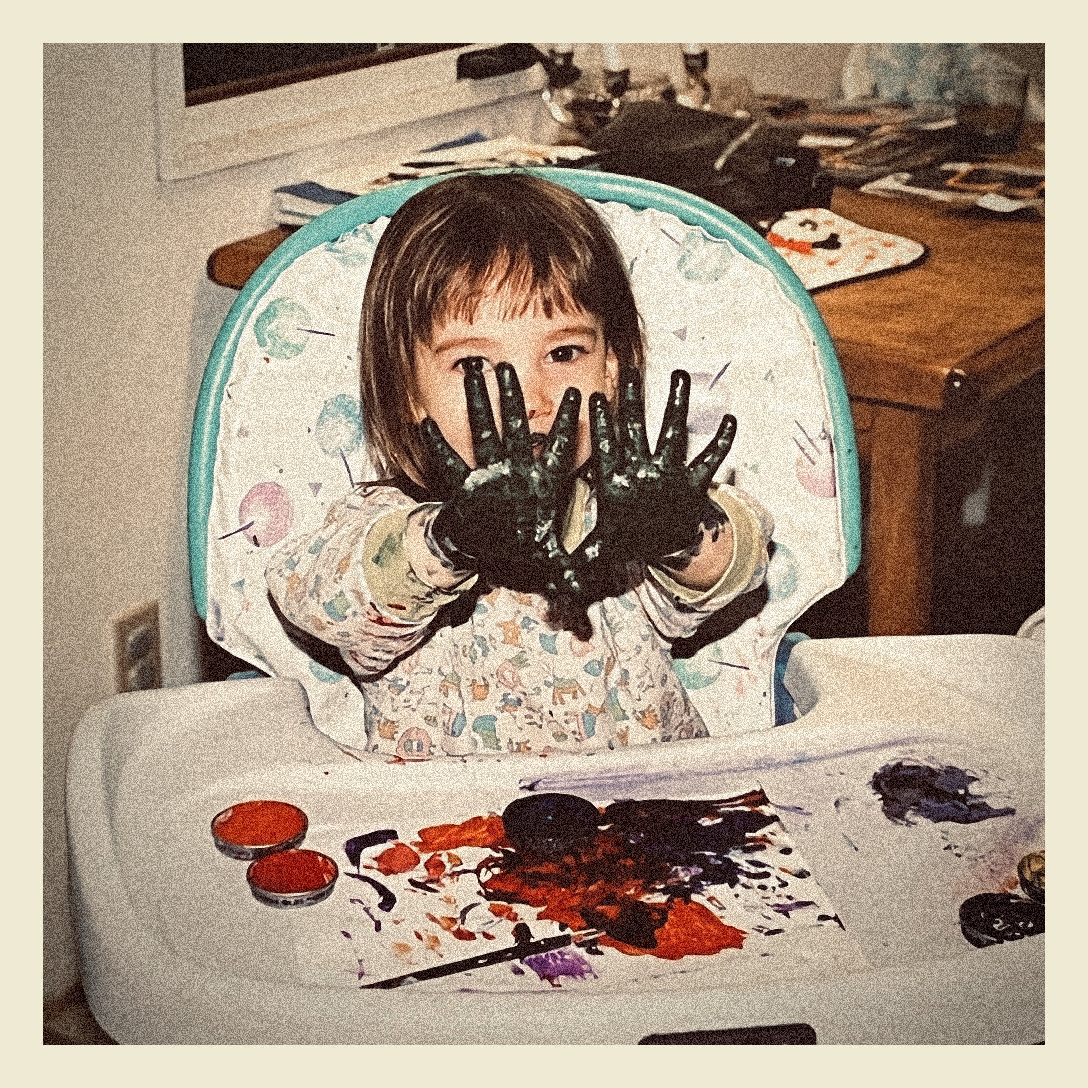A child's high chair with a Halloween-themed design featuring a child's face with a painted face mask, behind a painted hand with black gloves, surrounded by decorated pumpkins and splattered paint resembling blood.