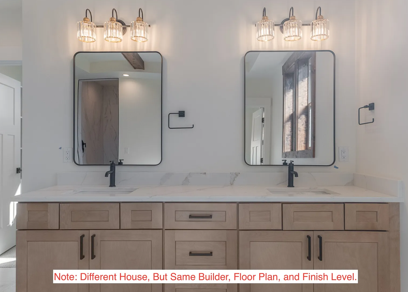 Double vanity bathroom with two mirrors, black faucets, light fixtures above, wooden cabinets, and a marble countertop.