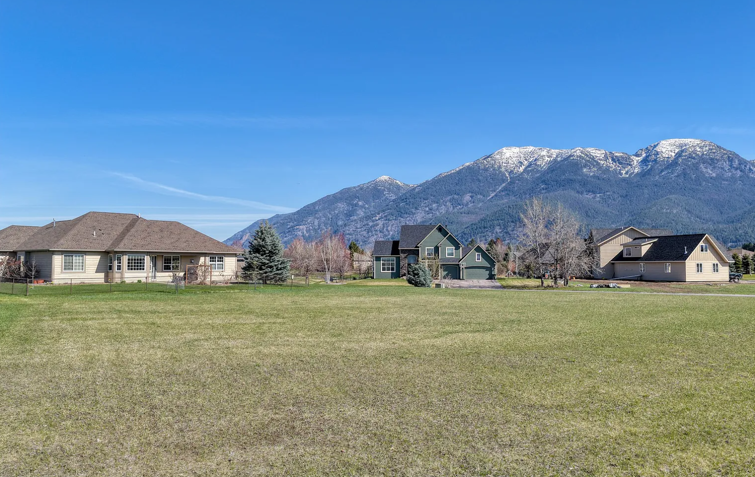 A row of houses with a mountain range in the background under a clear blue sky.