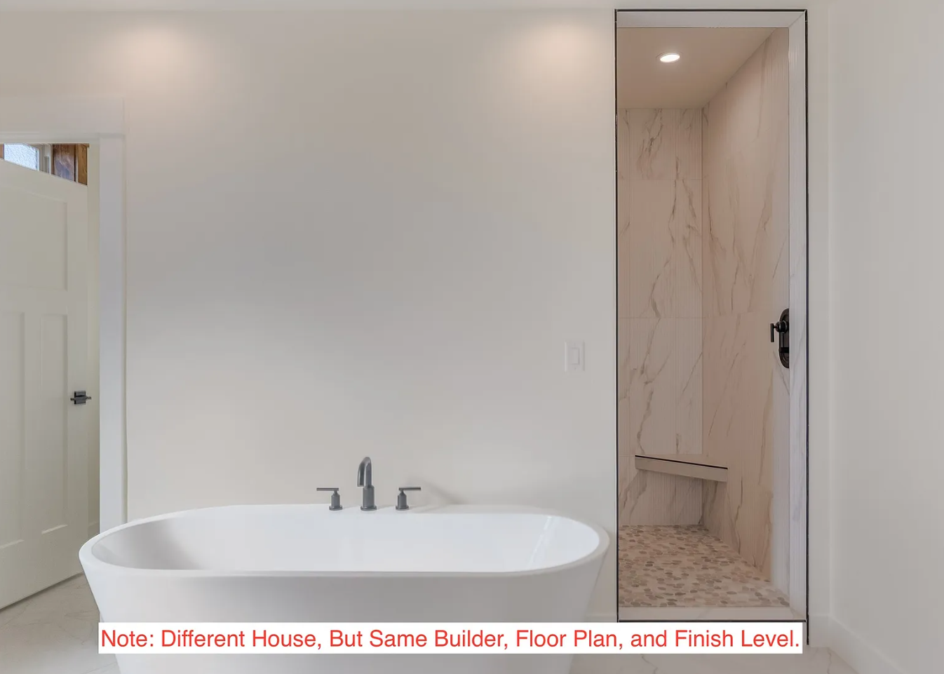 A modern bathroom featuring a white freestanding bathtub with gray fixtures and a walk-in shower with marble walls and pebble flooring.