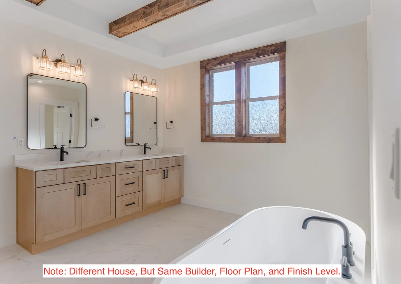 Bathroom with dual vanity, two mirrors, black fixtures, and a large window with wooden trim.