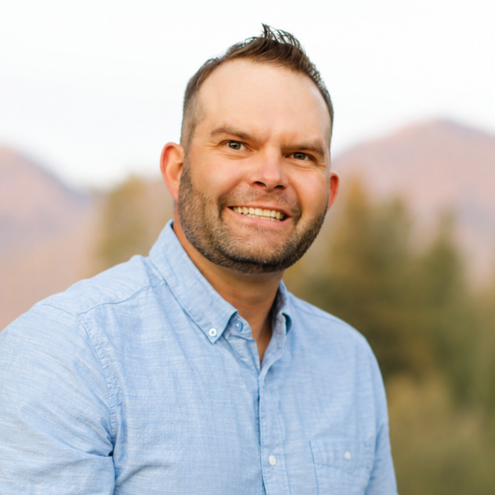 Portrait of a smiling man outdoors with mountains and trees in the background