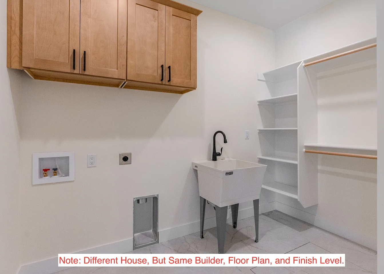 Empty laundry room with wooden cabinets, white shelving, a utility sink with a black faucet, and laundry hookups on the wall.