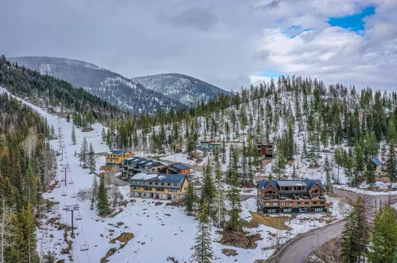 A snowy mountain landscape with ski lifts and several houses.