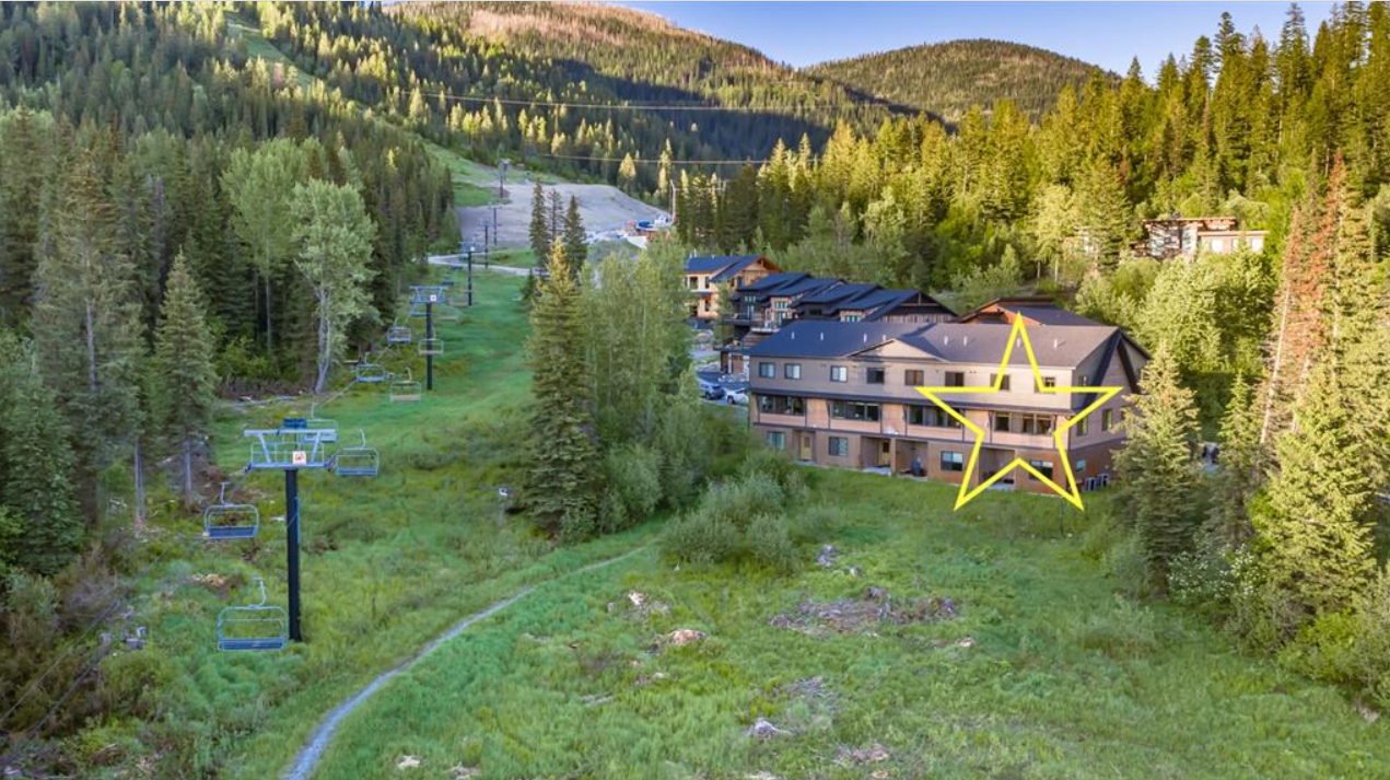 A mountain resort with a ski lift running through a forested area, with several buildings at the base and a large yellow star drawn on one of the buildings.