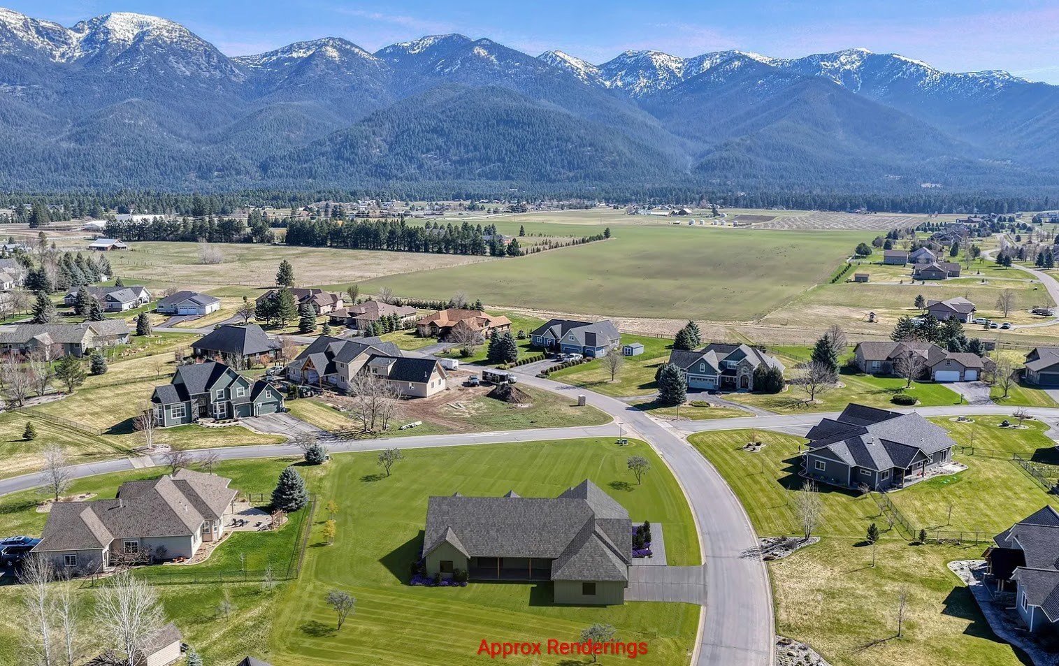 Aerial view of a suburban neighborhood with houses, roads, and green lawns, with mountains in the background.