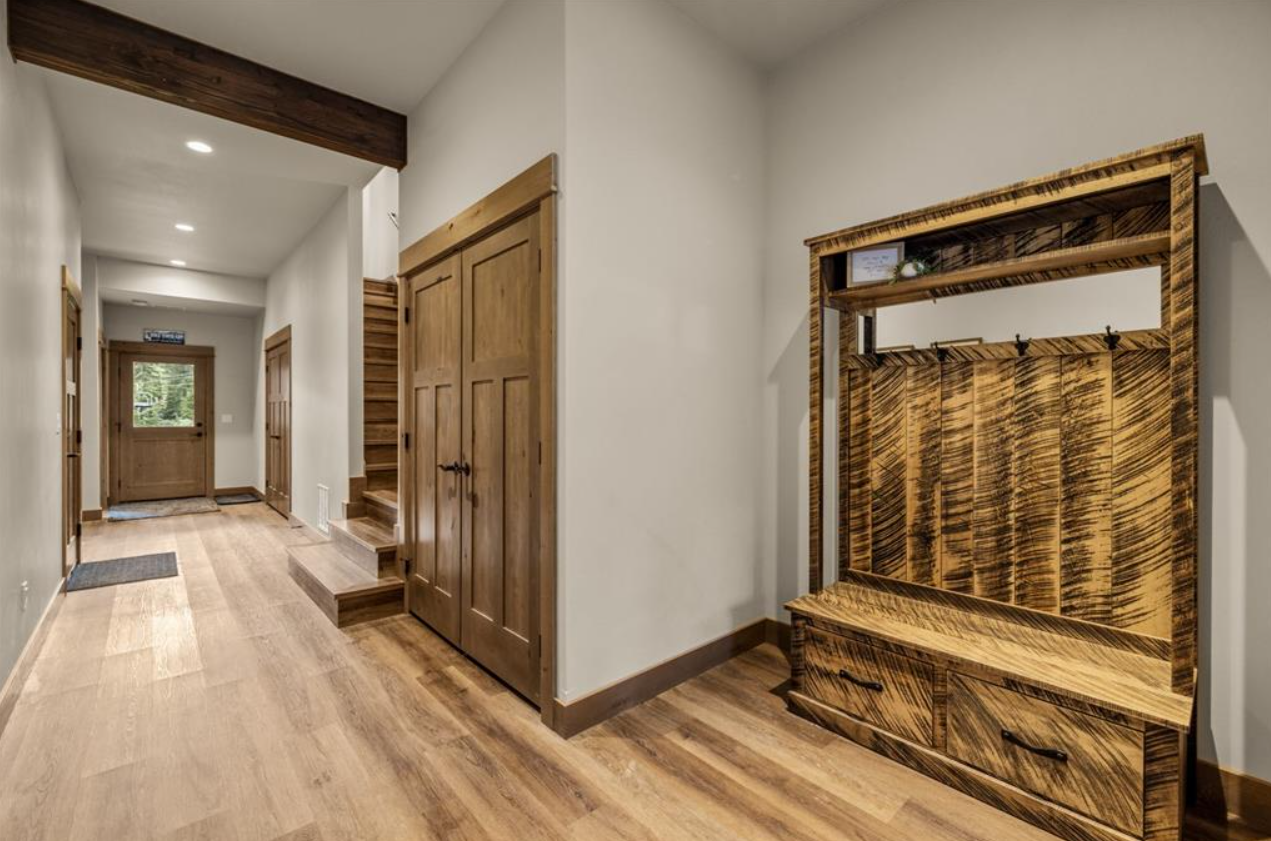 Interior hallway with wood accents, wooden doors, stairs, and a wooden hall tree with hooks and drawers.