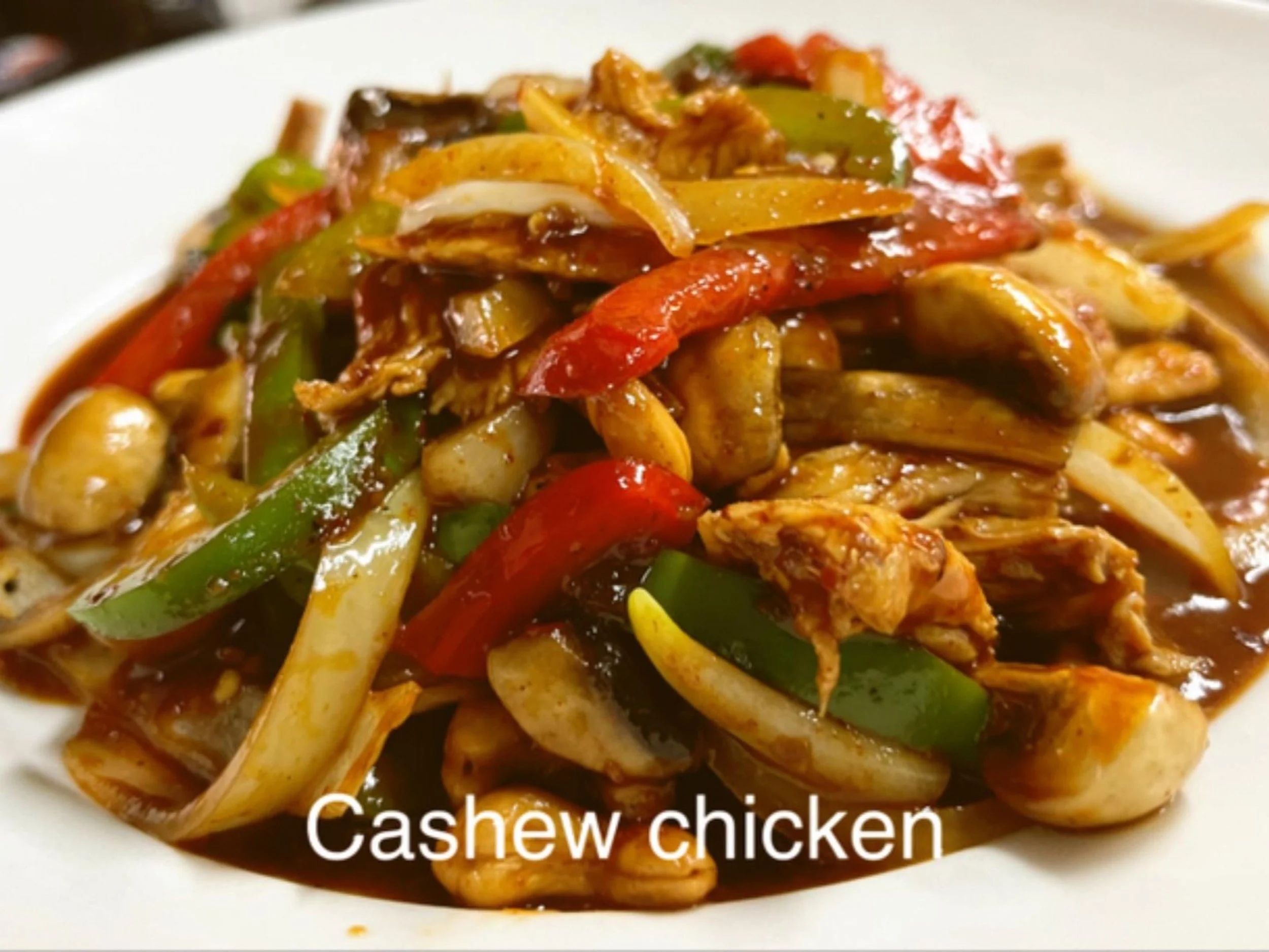 Plate of cashew chicken with sliced bell peppers, onions, and sauce