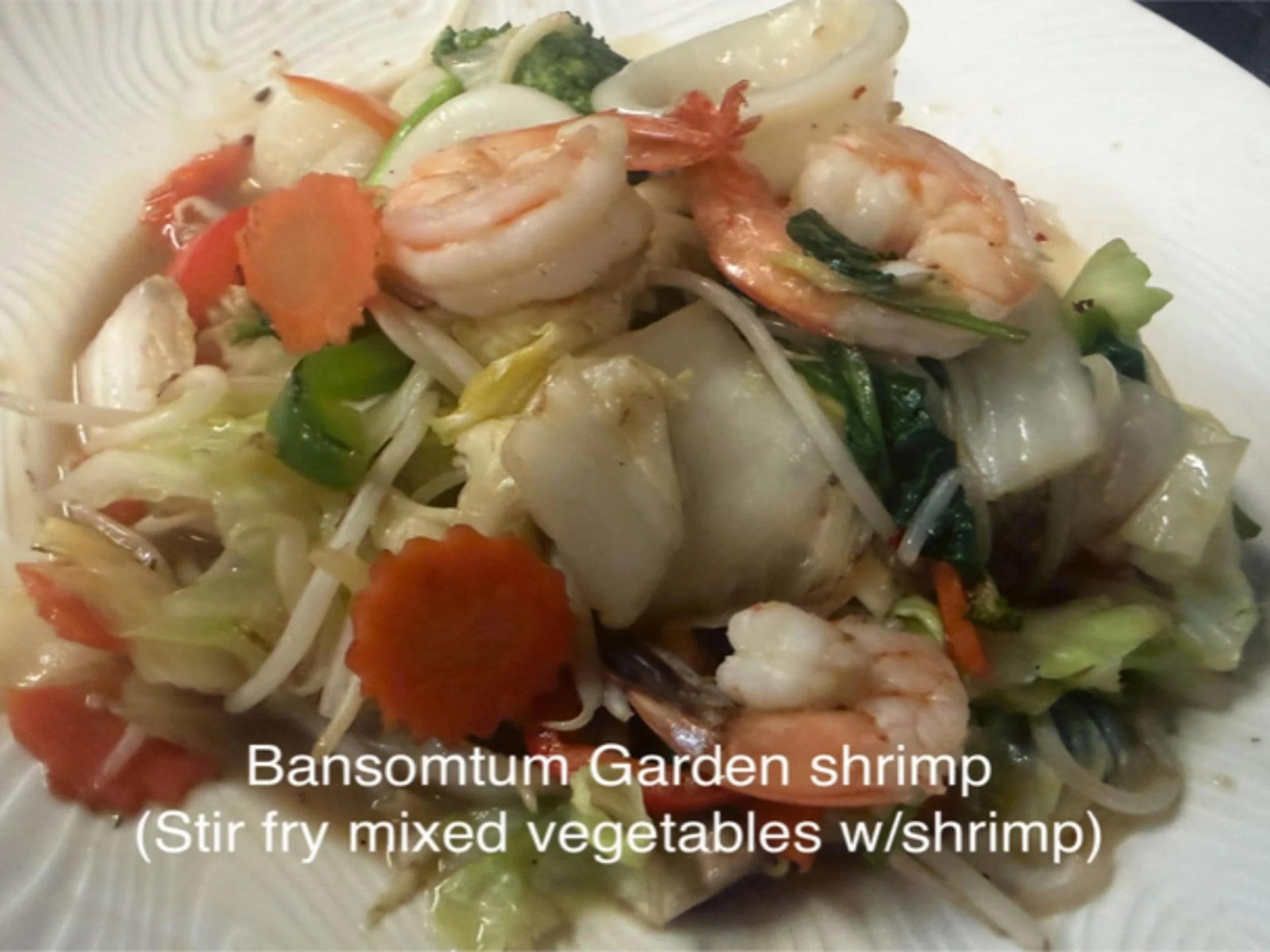 A plate of stir-fried mixed vegetables with shrimp, including carrots, broccoli, snap peas, bean sprouts, and cabbage.