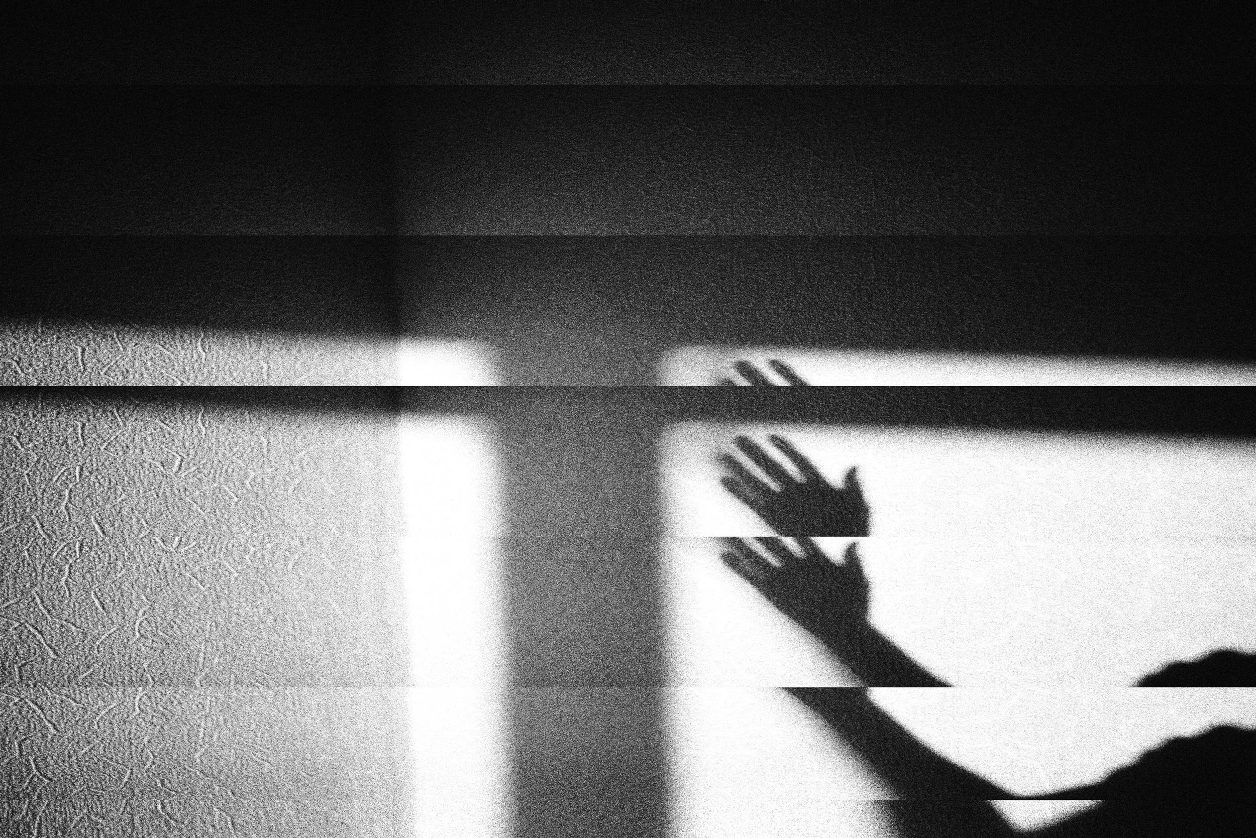 Black and white photo showing a shadow of a person's hands on a wall, with the shadow cast by a nearby light source.