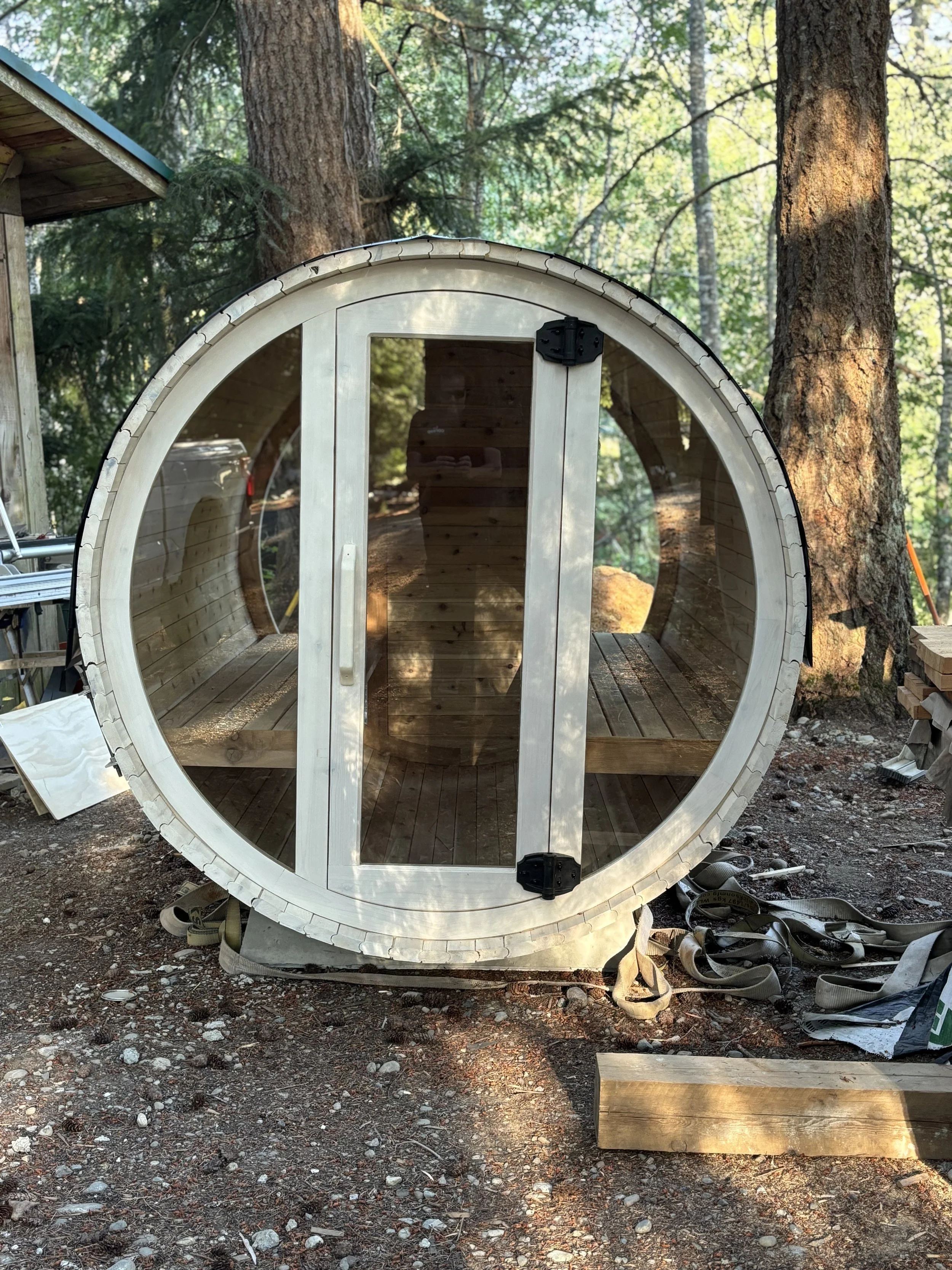 Cedar barrel sauna with a bright whitewashed finish and full glass door.