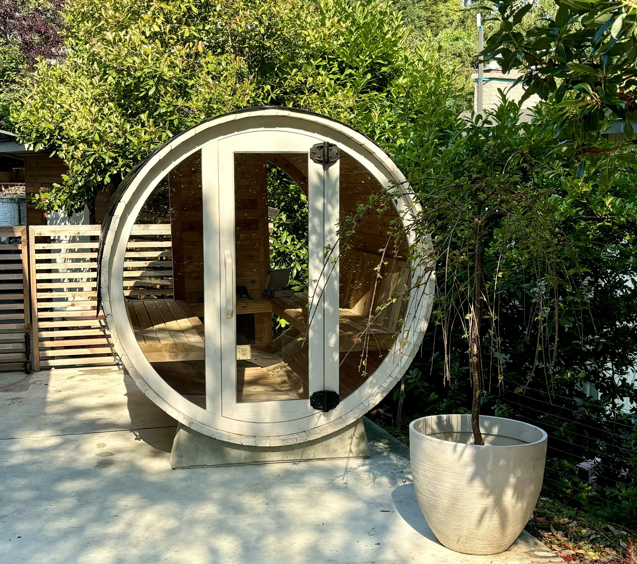 Cedar barrel sauna with a bright whitewashed finish and full glass front.