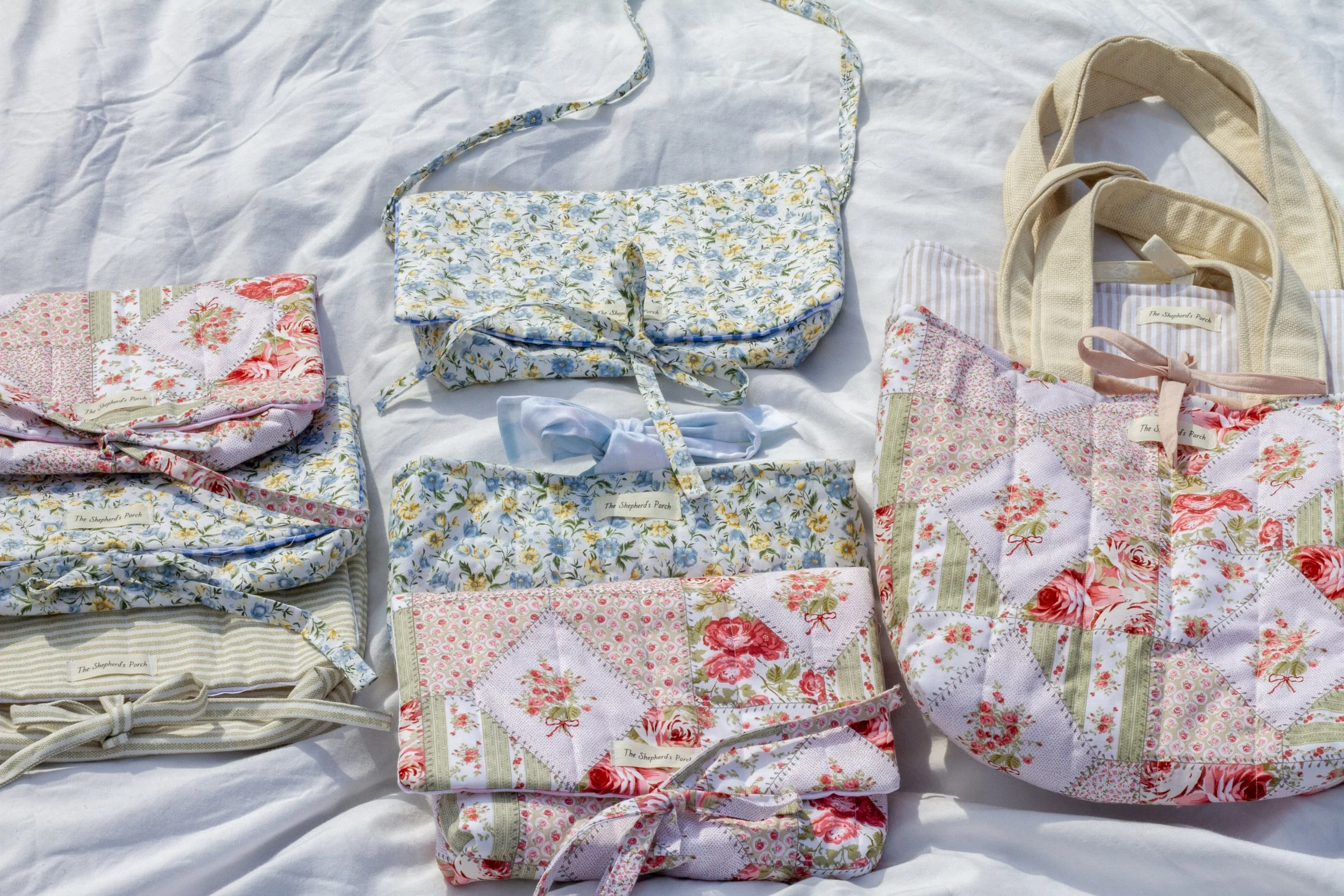 Multiple quilted fabric bundles with floral patterns and labels, laid out on a white surface.