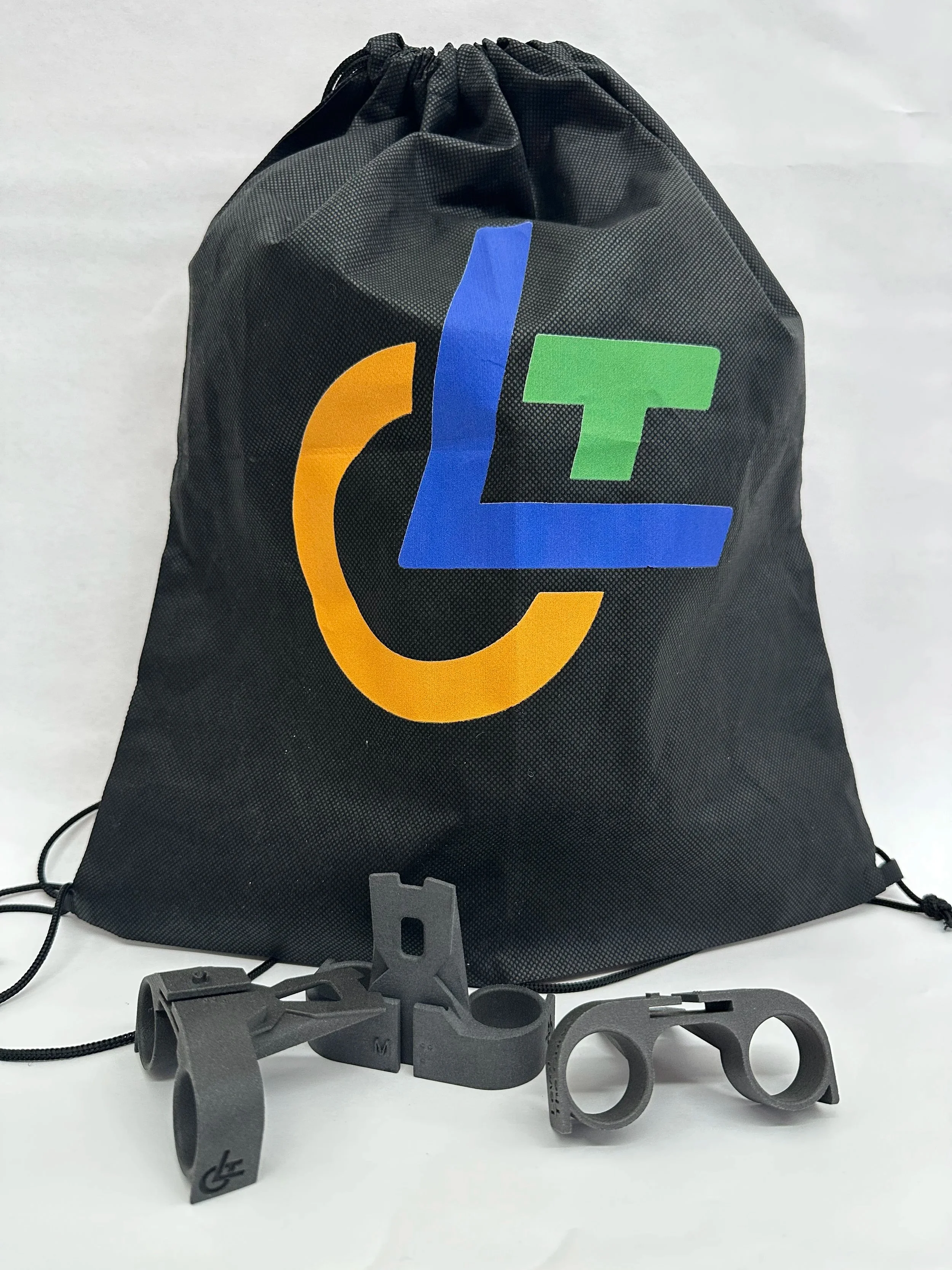 A black drawstring bag with colorful logo design and several gray plastic tools in front of it.
