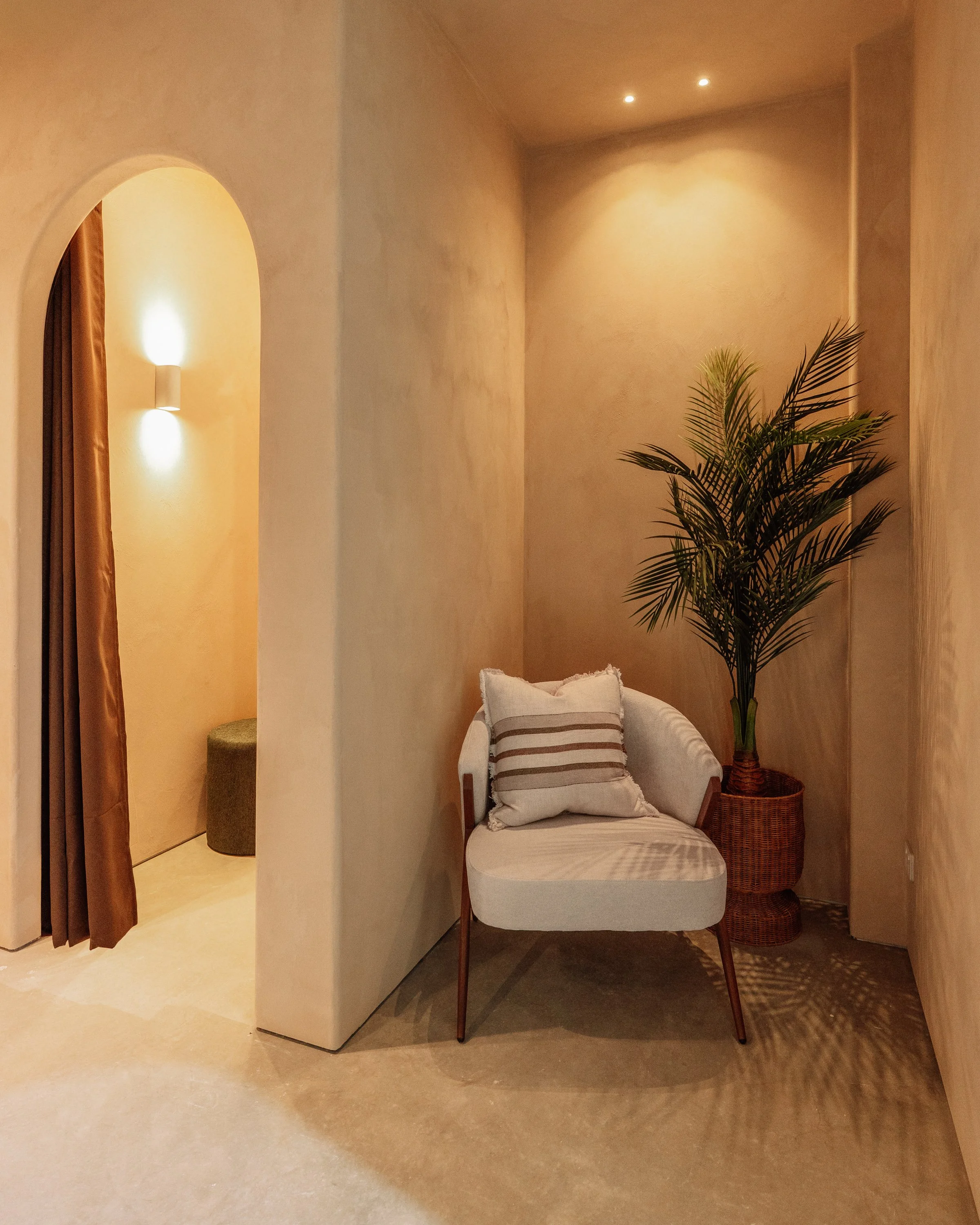 Change room and sitting area with textured walls, warm lighting, seating and a plant