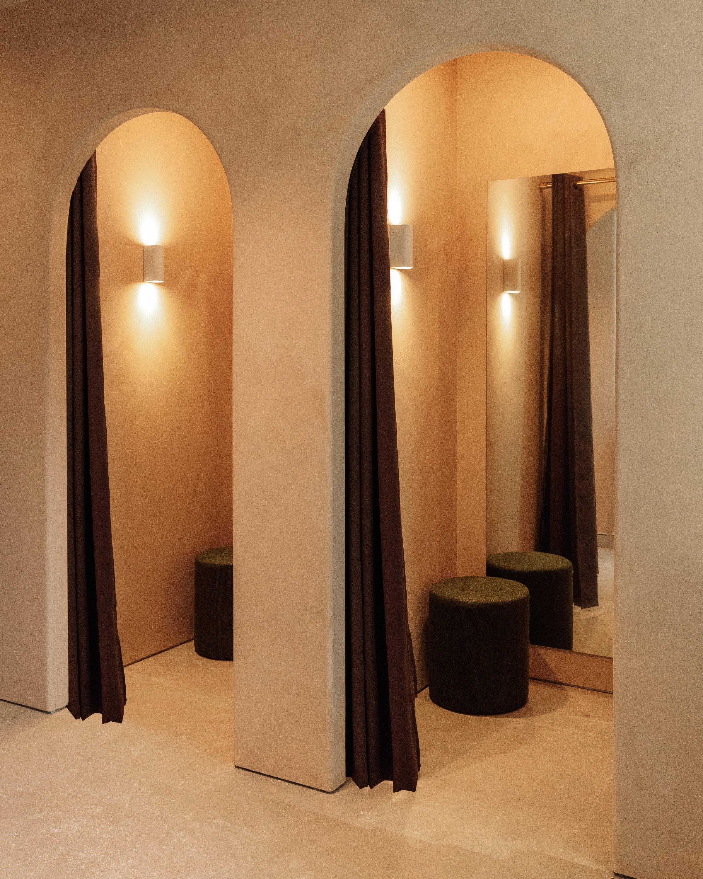 Arched change rooms with textured walls, fitted out with mirror, curtain and stool